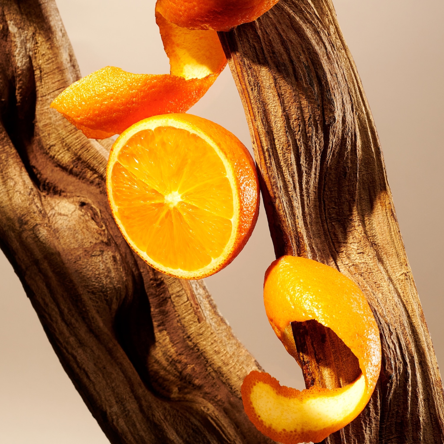 Eine halbe Orange und Orangenschalen liegen auf einem braunen Holzstück.