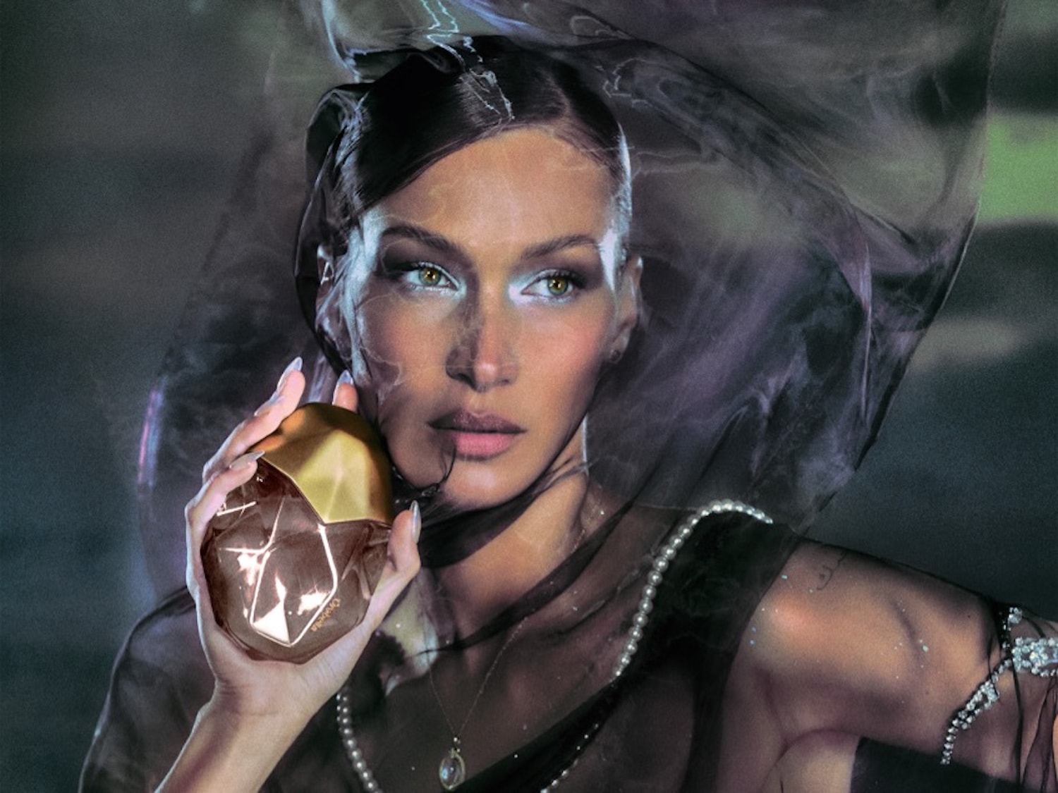 Eine Frau mit einem transparenten Schleier hält einen braunen, facettierten Flakon mit goldenem Deckel in der Hand.