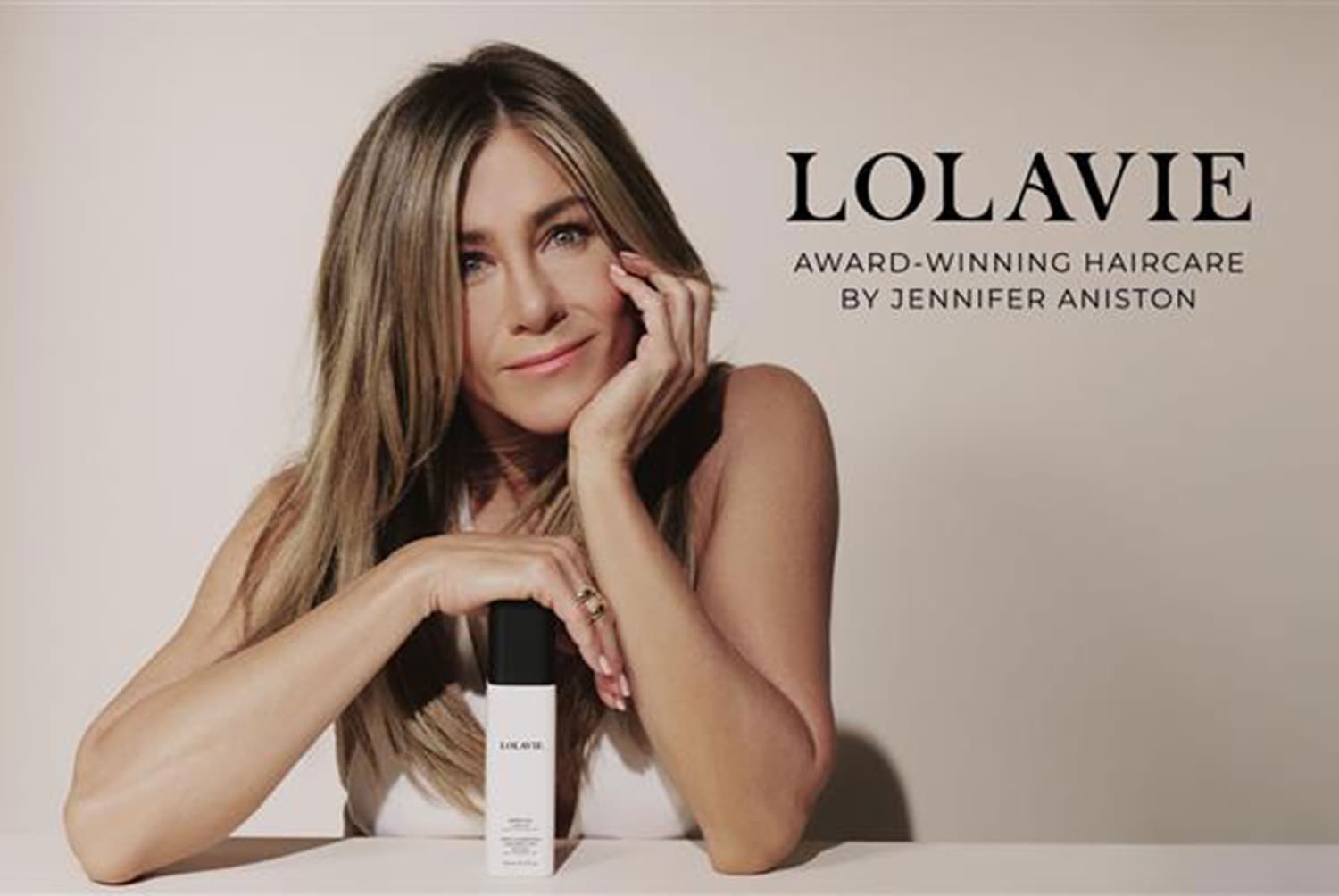 Jennifer Aniston présente Lolavie, une marque de soins capillaires primée, avec un flacon blanc et noir élégant.