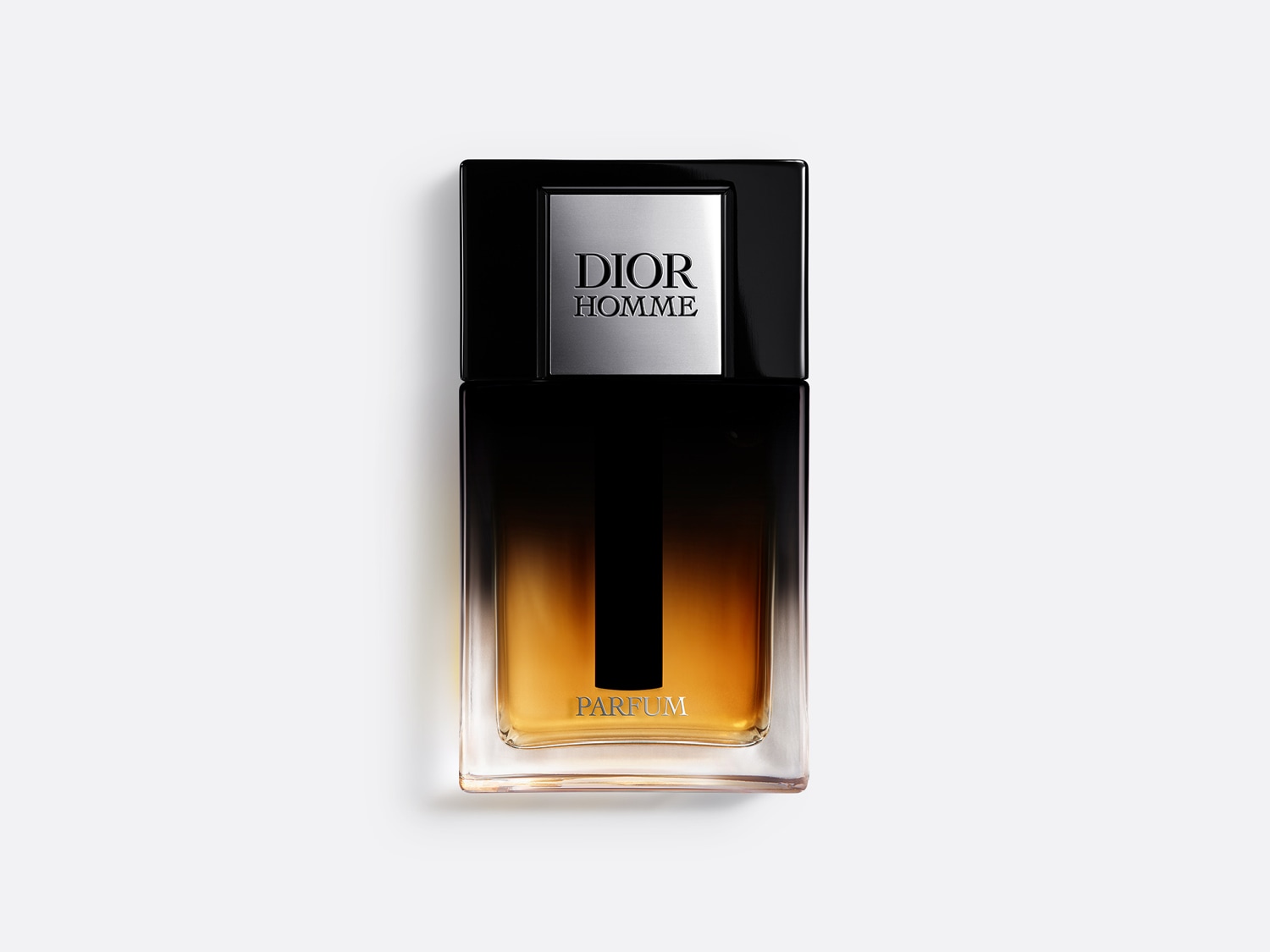 Sticlă dreptunghiulară de parfum Dior Homme, cu capac negru lucios și etichetă argintie, conținând un parfum auriu închis care se întunecă spre negru în partea superioară.