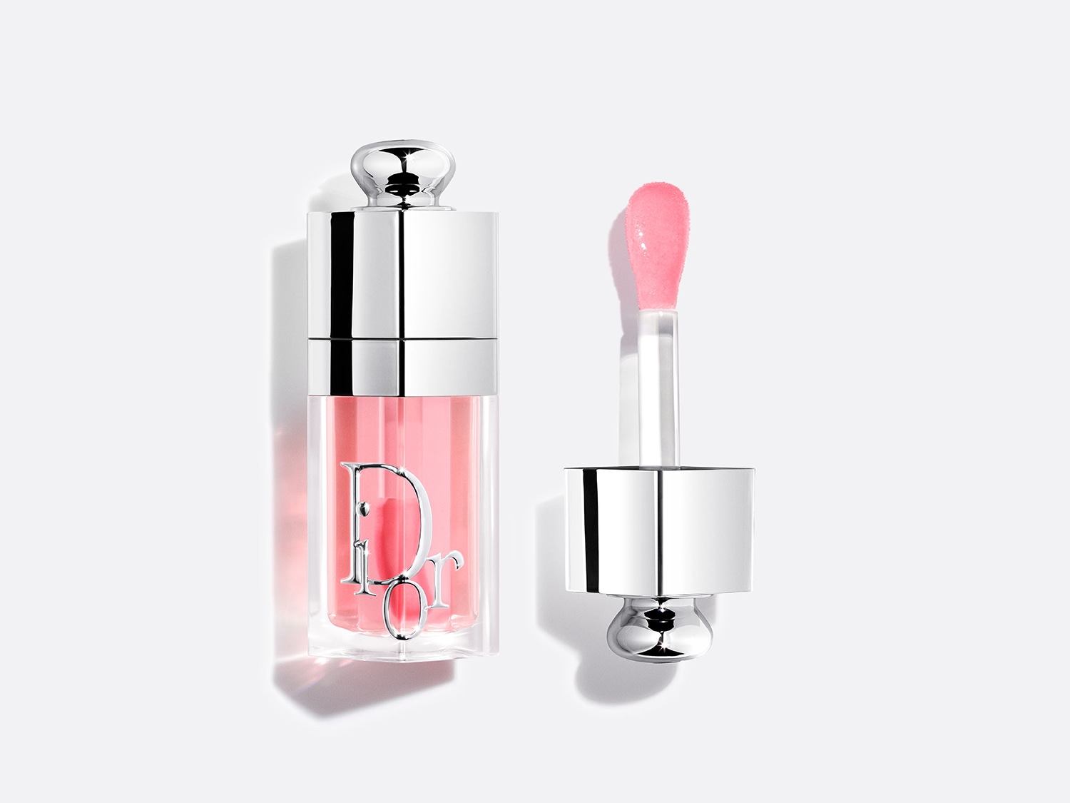 Brillant à lèvres Dior, teinte rose pâle, dans un flacon transparent avec bouchon argenté et applicateur.