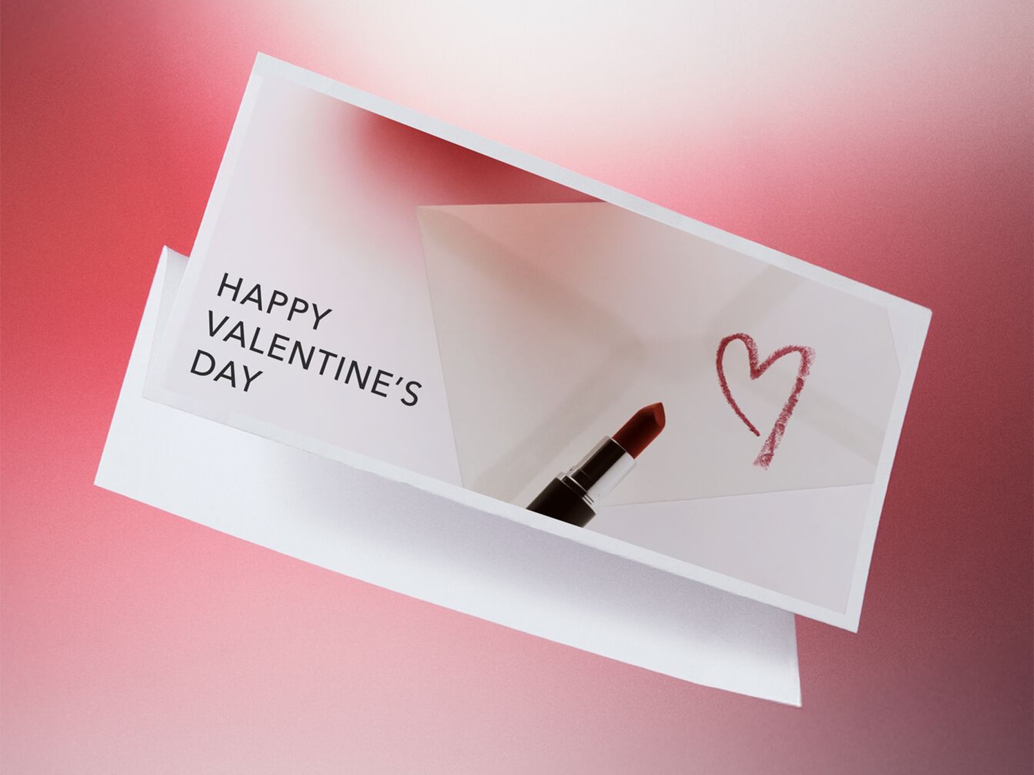 Eine Karte zum Valentinstag mit der Aufschrift "Happy Valentine's Day", einem mit Lippenstift gezeichneten Herz und einem Lippenstift selbst.