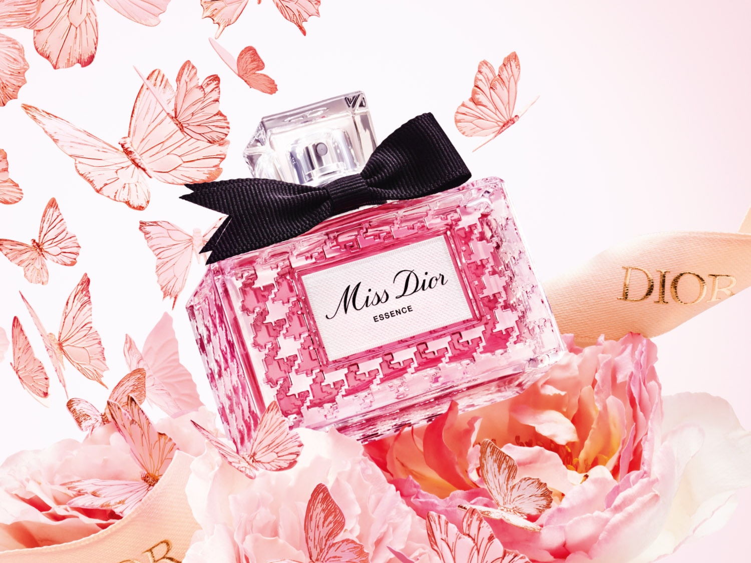 Roze Miss Dior Essence parfumfles met zwarte strik, omringd door roze bloemen en vlinders, met een DIOR-lint.