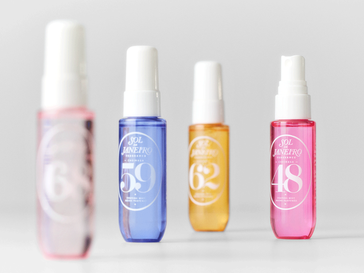 Vier Sol de Janeiro Körpersprays in Rosa, Blau, Gelb und Pink mit weißer Schrift und Sprühkopf.