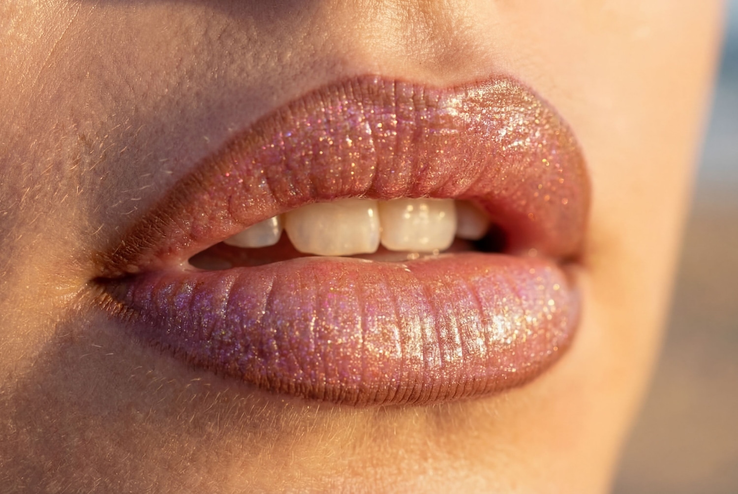 Nahaufnahme von glänzenden, rosafarbenen Lippen mit leicht geöffnetem Mund, die die weißen Zähne zeigen.