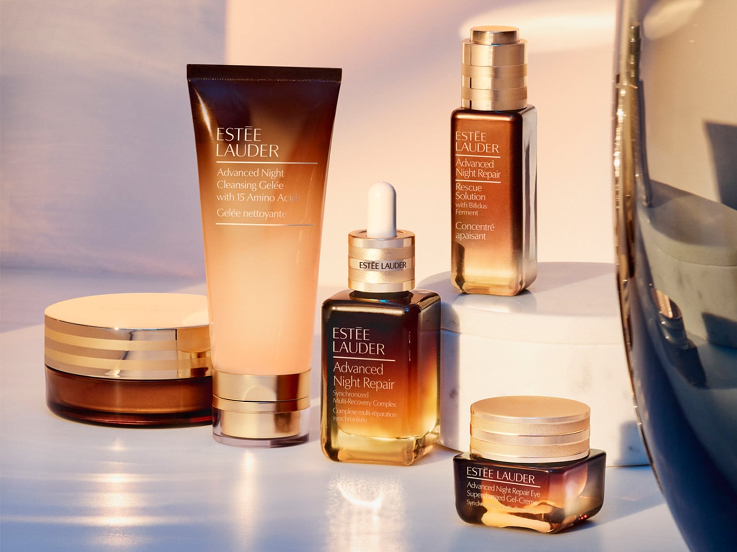 Eine Sammlung von Estée Lauder Advanced Night Repair Produkten, darunter Cleansing Gelée, Rescue Solution und Augenpflege in luxuriösen Verpackungen.