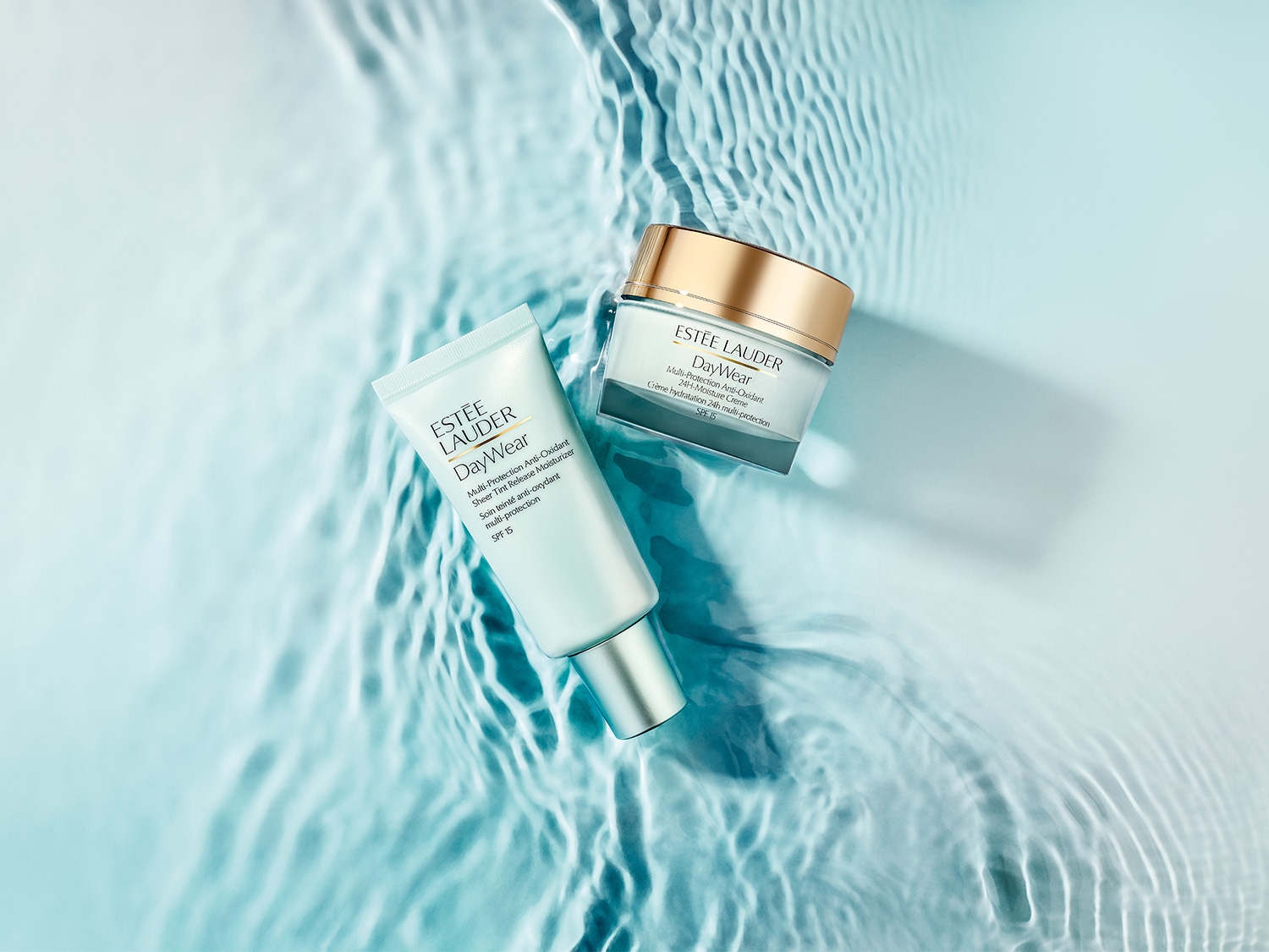 Estée Lauder DayWear: Eine Tube mit getönter Feuchtigkeitspflege und ein Tiegel mit Feuchtigkeitscreme mit Lichtschutzfaktor liegen auf einer Wasseroberfläche.