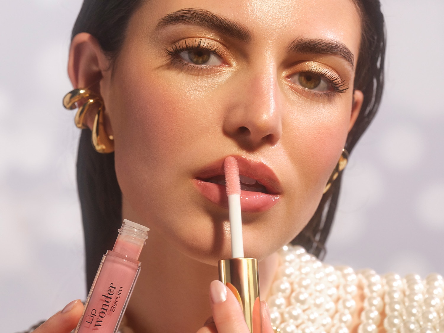 Nahaufnahme einer Frau, die das ARTDCO Lip Wonder Serum mit einem Applikator mit goldenem Deckel auf ihre Lippen aufträgt.