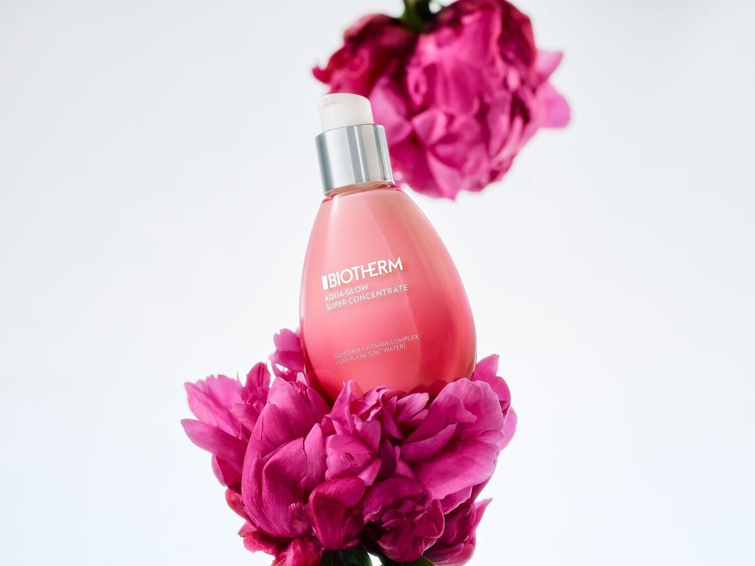 Šis „Biotherm Aqua Glow Super Concentrate“ serumas yra rausvos spalvos buteliuke su sidabriniu dozatoriumi, apsuptas ryškiai rožinių bijūnų žiedų.