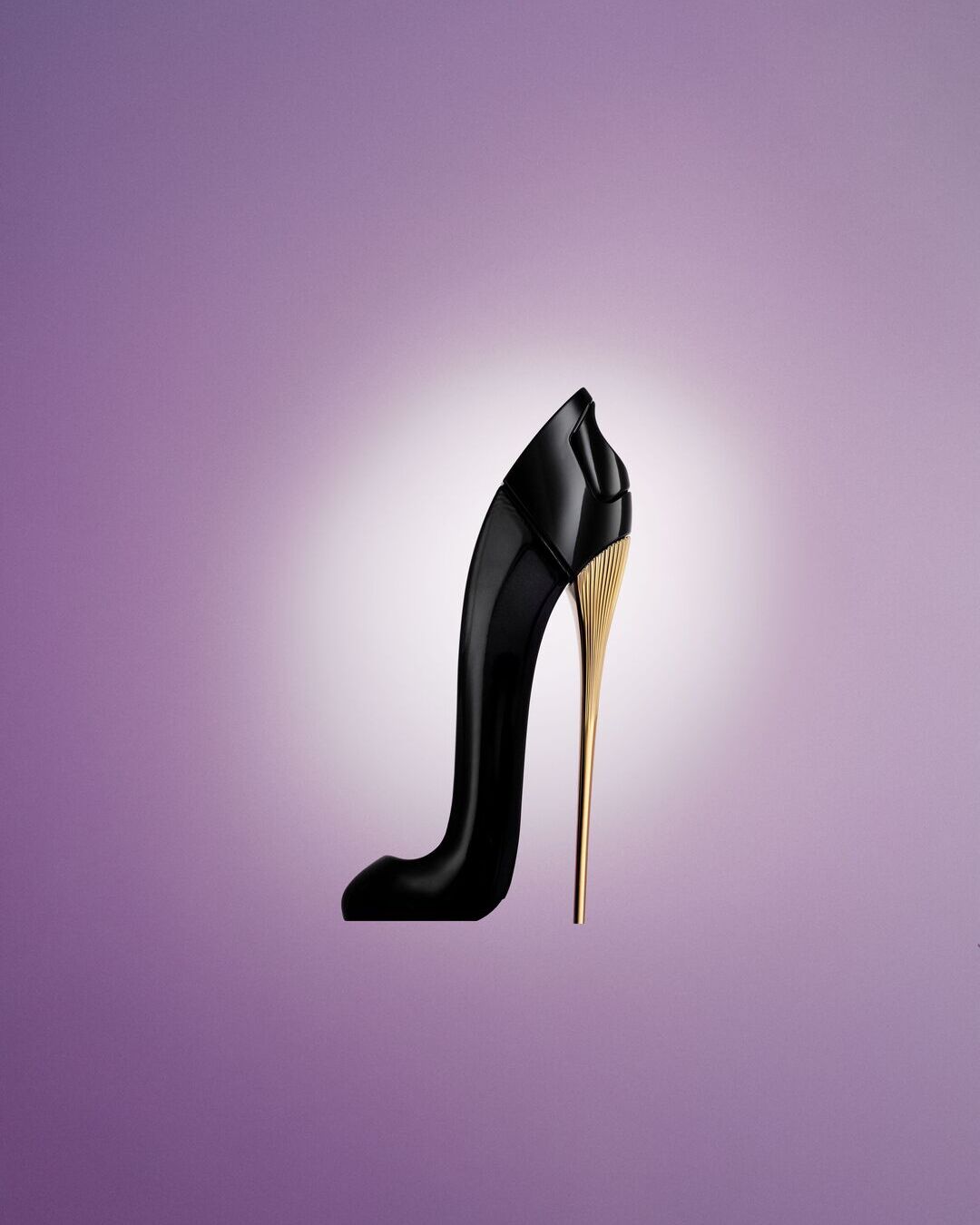 Elegantiškas juodas aukštakulnio formos kvepalų buteliukas su auksiniu kulnu ant švelnaus violetinio fono.