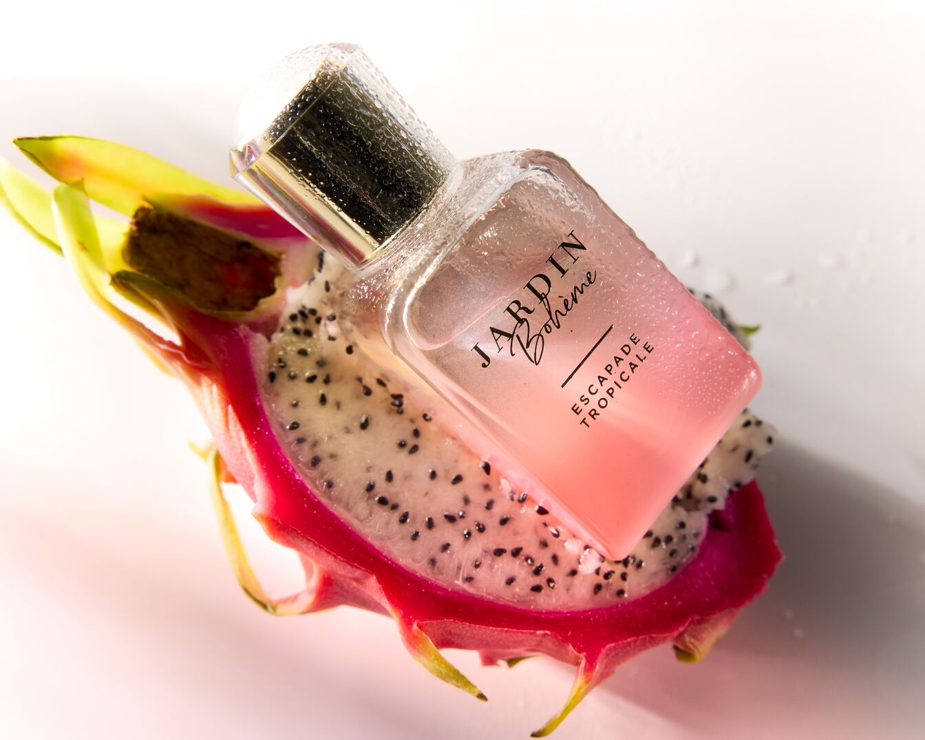 Le parfum Jardin Bohème Escapade Tropicale repose sur une tranche de fruit du dragon, évoquant un parfum exotique et frais.