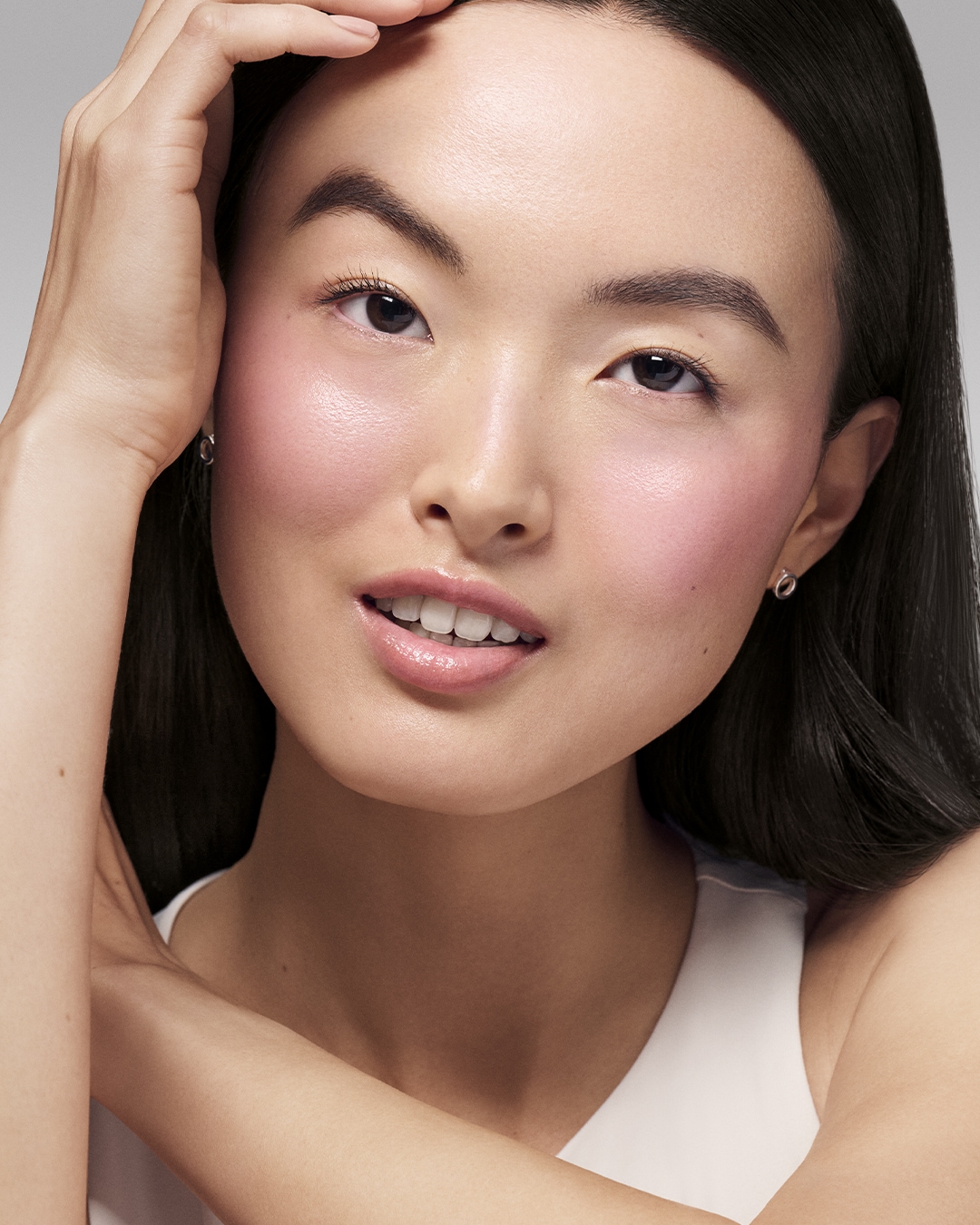 Primer plano de una mujer asiática con la piel sonrosada y brillante, resaltando un maquillaje natural y fresco.