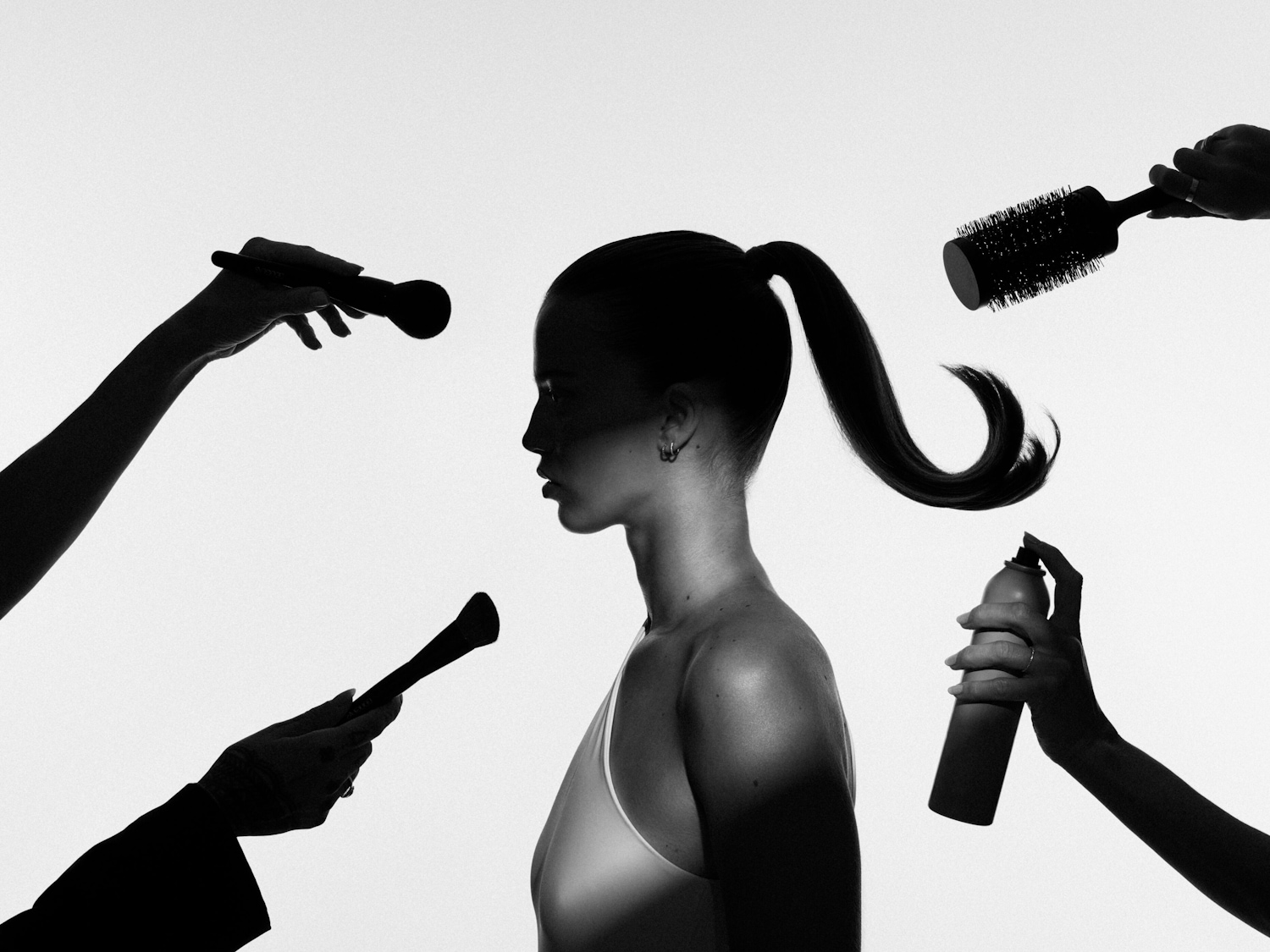 Silhouette einer Frau im Profil, umgeben von Händen, die Make-up-Pinsel, eine Rundbürste und Haarspray halten, was auf eine Schönheitsbehandlung oder ein Styling-Session hindeutet.