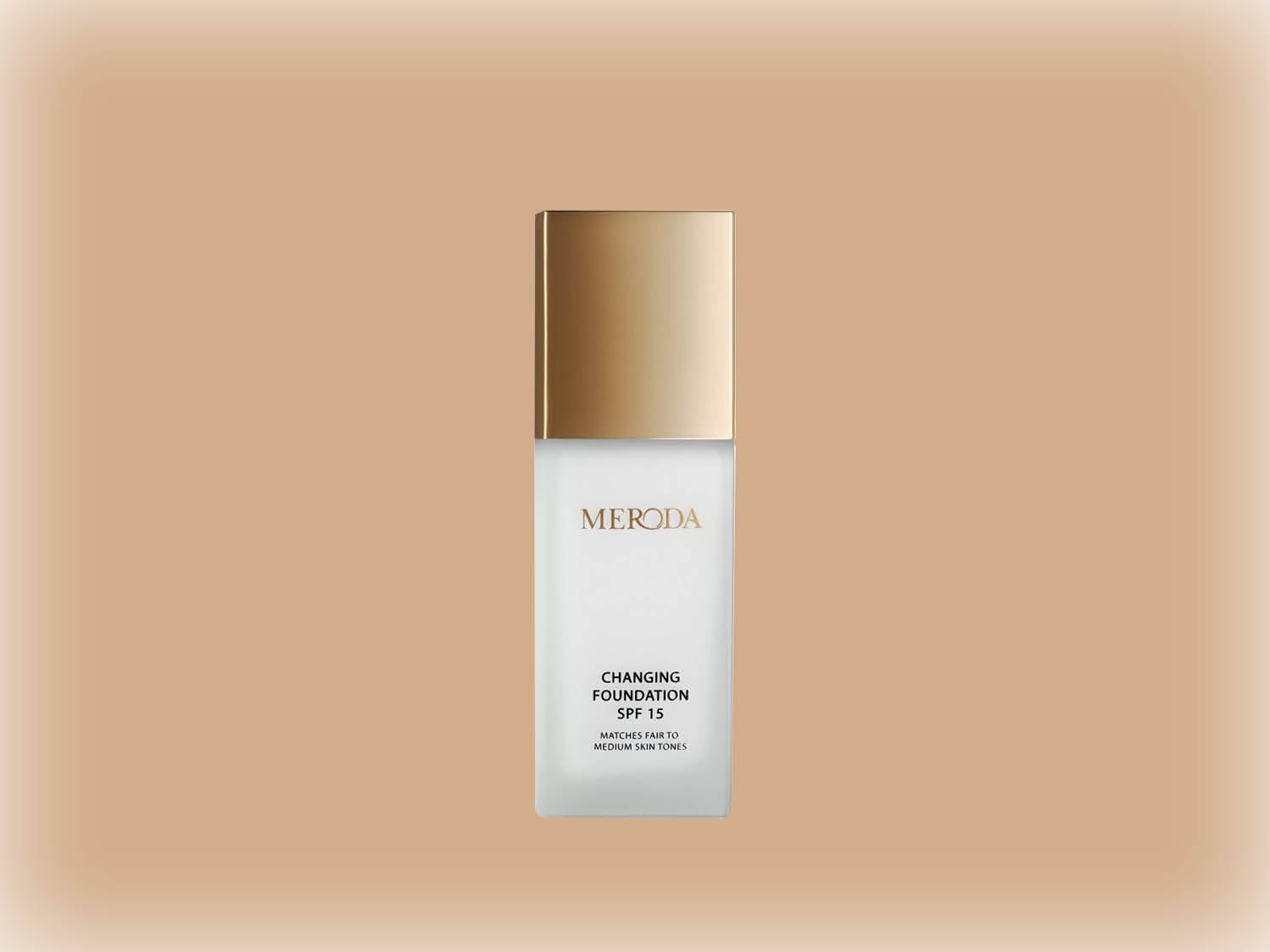 Voici le fond de teint changeant MERODA SPF 15, dans un flacon carré blanc givré avec un bouchon doré, conçu pour les teints moyens.