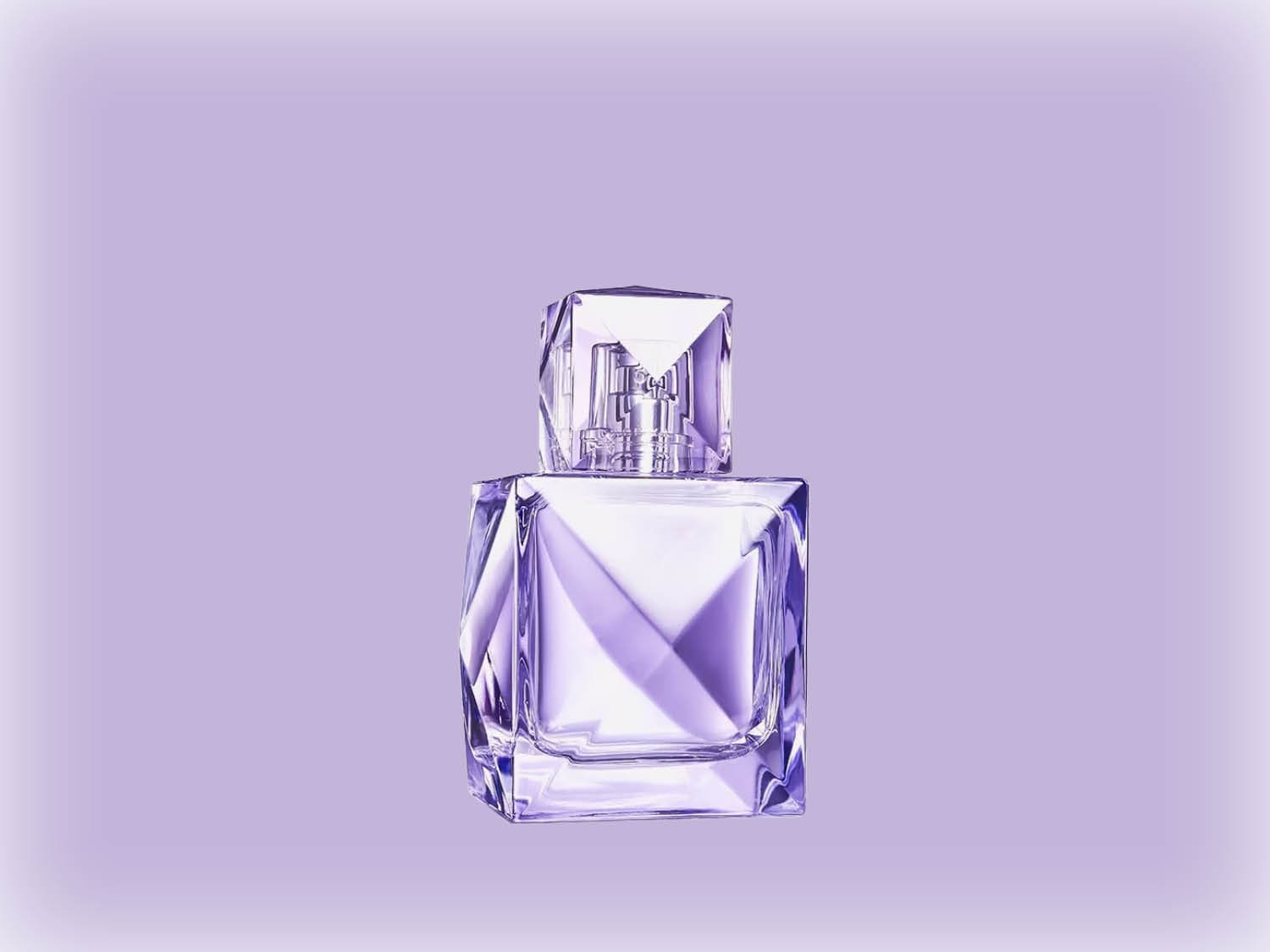 Voici un flacon de parfum en verre transparent aux reflets violets, avec un bouchon taillé en forme de diamant, sur un fond violet doux.