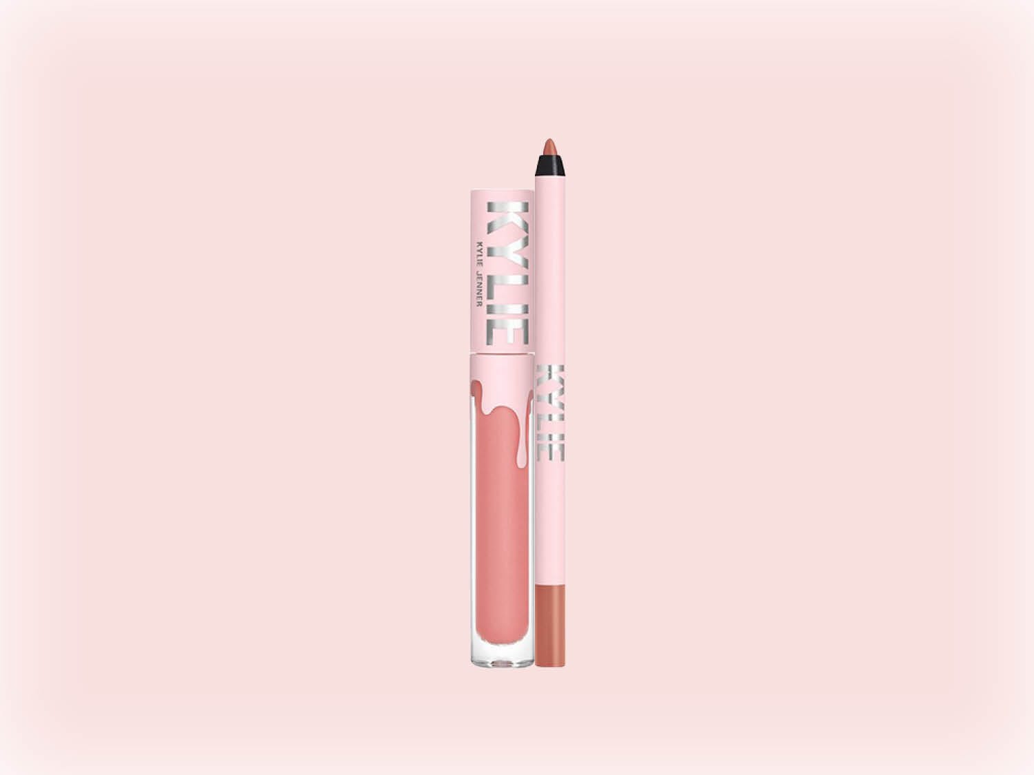 Voici un ensemble Kylie Cosmetics comprenant un rouge à lèvres liquide rose pêche avec un applicateur et un crayon à lèvres assorti, tous deux dans un emballage rose clair portant le nom de la marque.