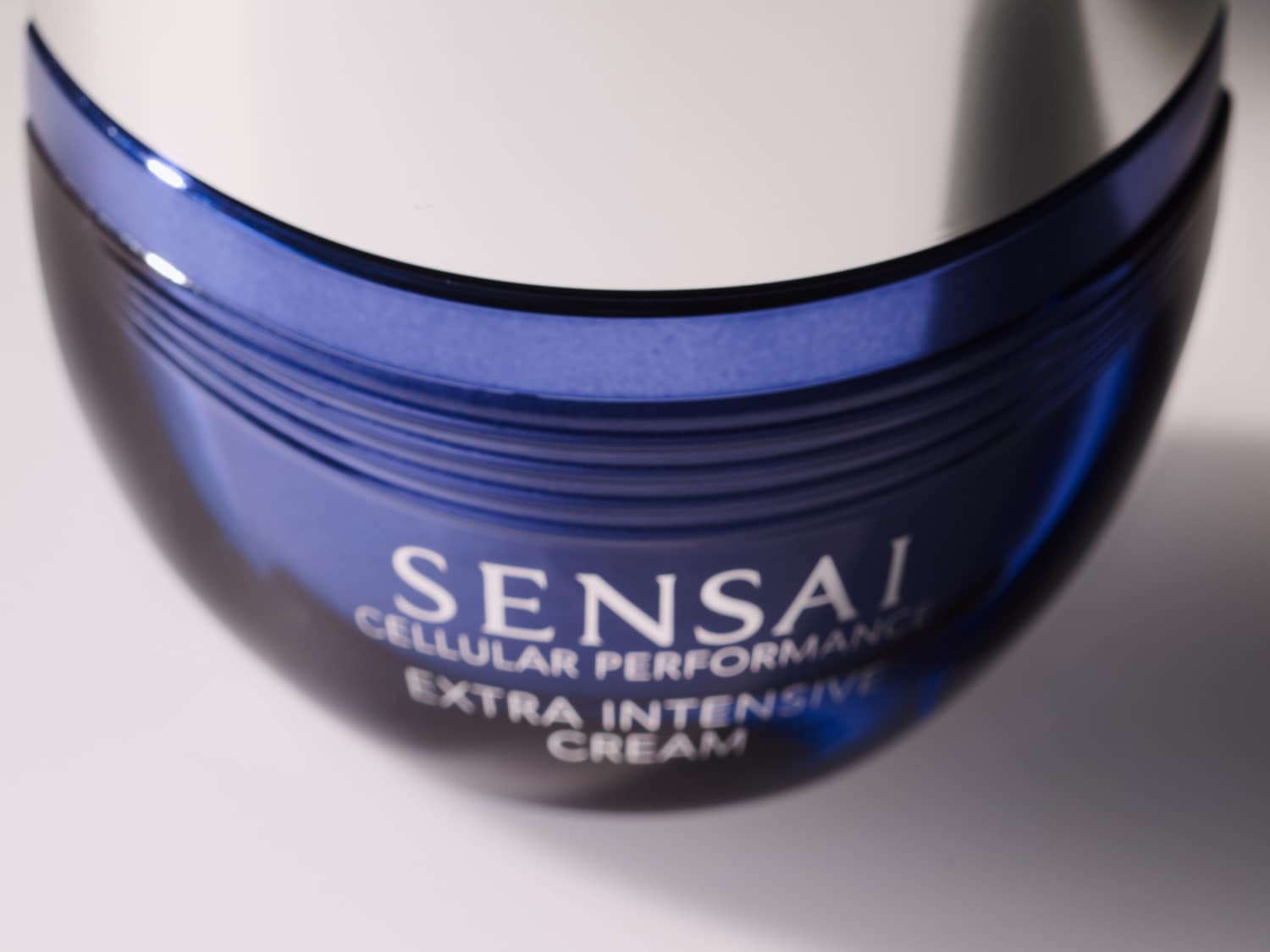 Detailní pohled na modrý kelímek Sensai Cellular Performance Extra Intensive Cream s bílým víčkem, který slibuje intenzivní péči o pleť.