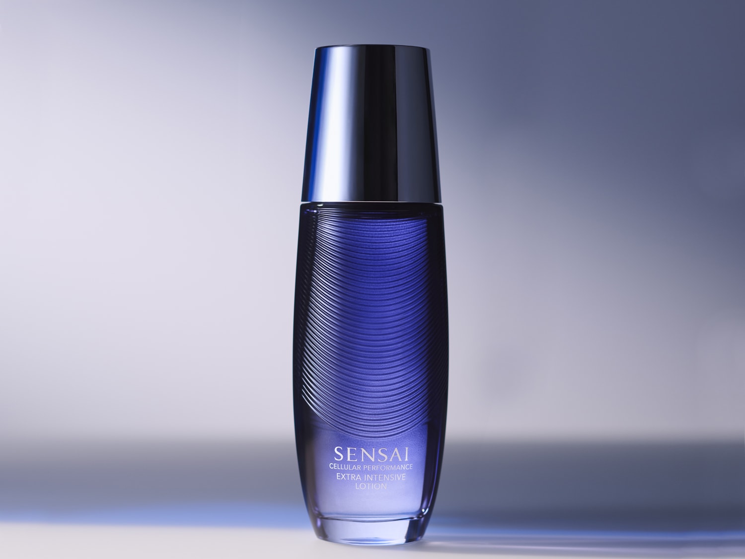 Lahvička Sensai Cellular Performance Extra Intensive Lotion má tmavě modré tělo s jemnými vodorovnými liniemi a lesklý černý uzávěr.