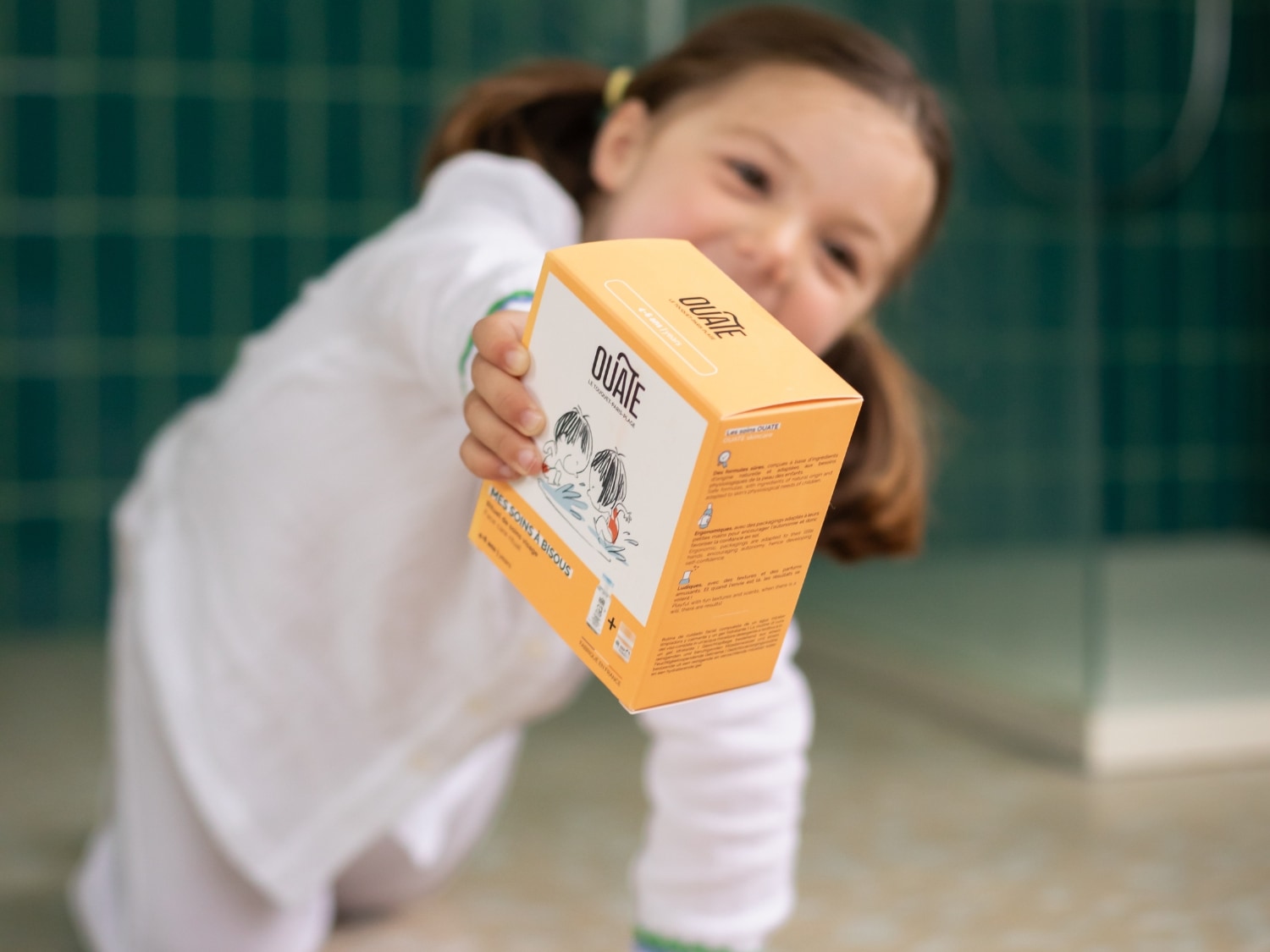 Enfant tenant un coffret de soins dans une salle de bain, produits de soin pour enfant.