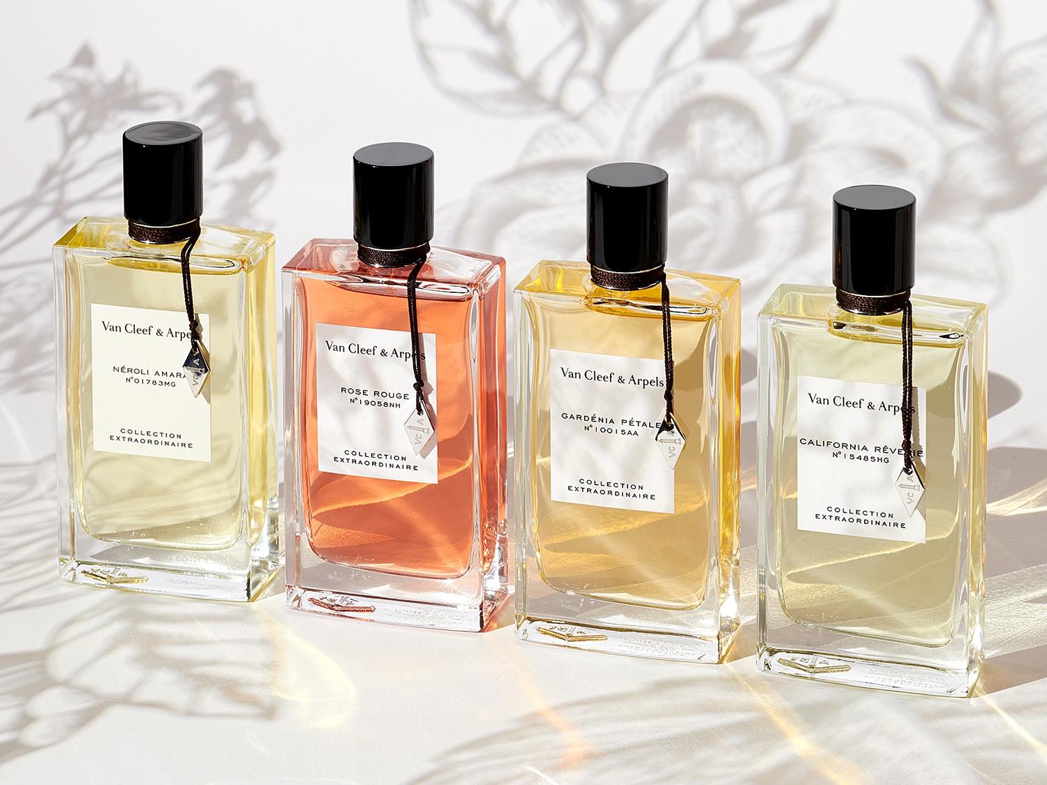 Quatre flacons de parfum Van Cleef & Arpels Collection Extraordinaire, chacun rempli d'un parfum de couleur différente : jaune clair, rose, jaune et jaune pâle.