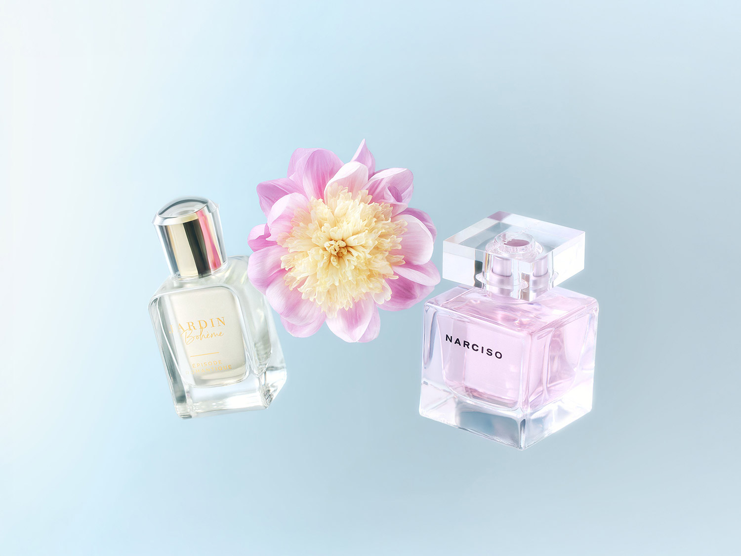 Découvrez le parfum Jardin Bohème dans un flacon en verre transparent et Narciso dans un flacon rose délicat, présentés avec une fleur rose et blanche sur un fond bleu doux.