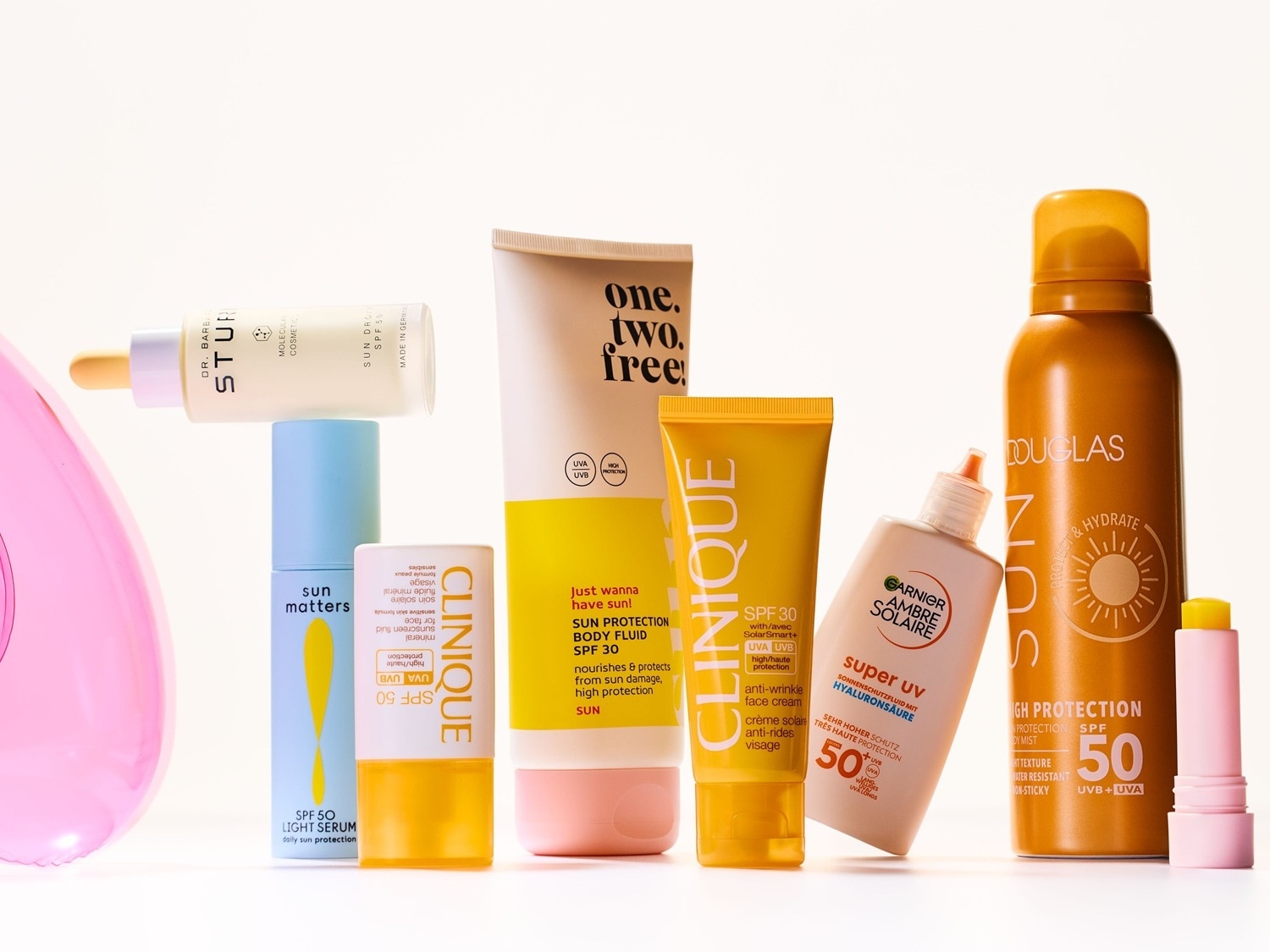 Eine Sammlung von Sonnenschutzprodukten verschiedener Marken wie Douglas, Garnier Ambre Solaire und Clinique, darunter Sprays, Fluide und Cremes mit hohem Lichtschutzfaktor.