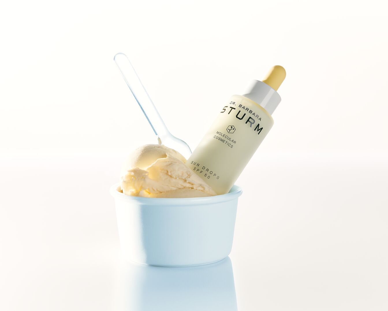 Dr. Barbara Sturm Sonnenschutz-Tropfen SPF 50 in einer hellblauen Schale mit Eis und einem durchsichtigen Löffel.