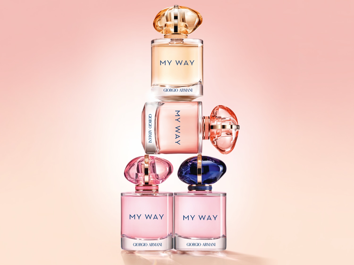 Na ružovom pozadí je pyramída fliaš parfumu Giorgio Armani My Way s rôznymi farebnými viečkami, ktoré vytvárajú hravú a elegantnú kompozíciu.