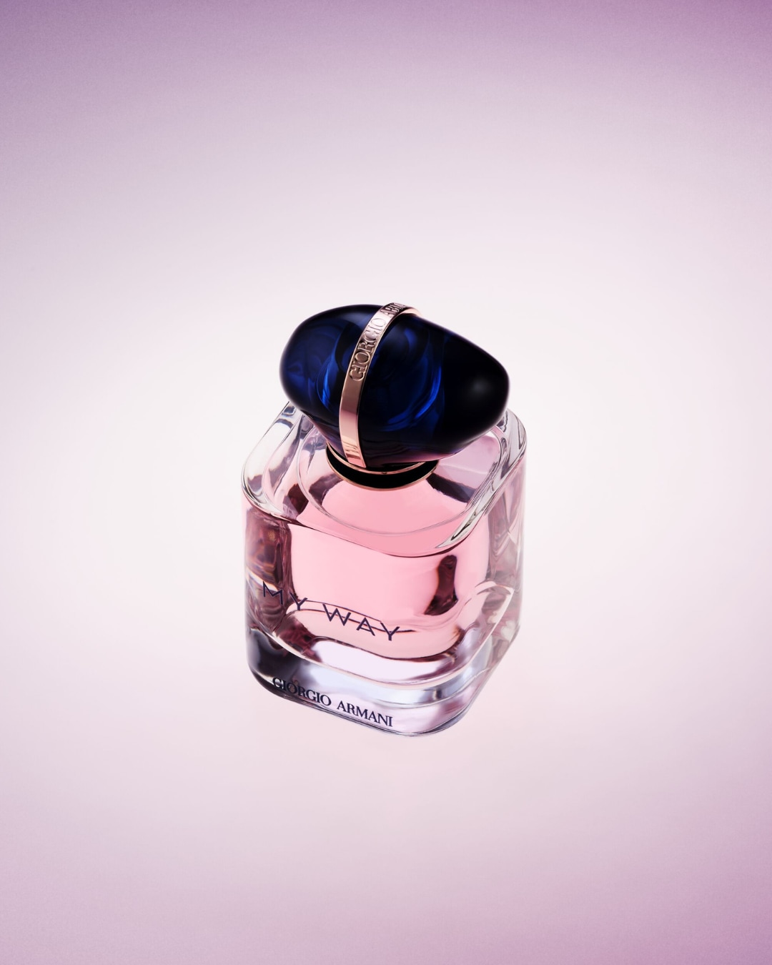 Een heldere glazen flacon met een zachtroze vloeistof, afgesloten met een donkerblauwe, marmerachtige dop en een gouden ring met de inscriptie 'Giorgio Armani'.