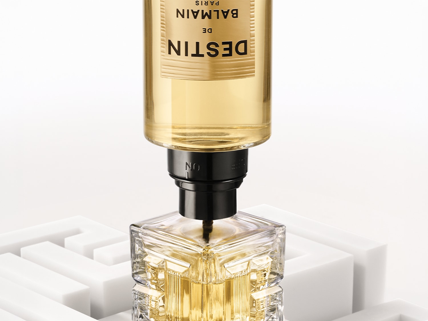 Il profumo Balmain de Destin Paris è racchiuso in un flacone di vetro trasparente con un tappo nero, che rivela una fragranza dorata e luminosa.