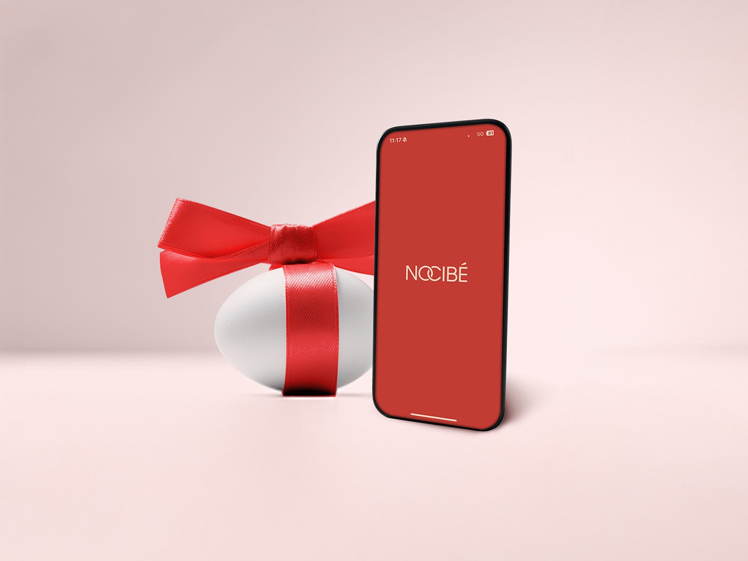 Découvrez l'application Nocibé, votre destination beauté idéale, présentée à côté d'un œuf de Pâques décoré d'un ruban rouge festif.