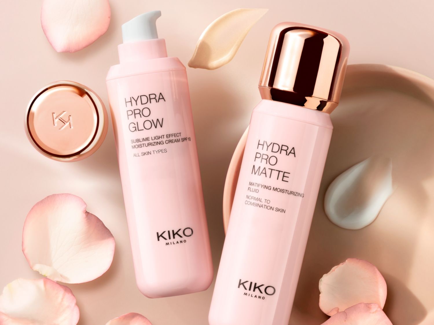 Zwei rosa KIKO Milano Hydra Pro Feuchtigkeitscremes, Glow mit Lichteffekt und SPF 10 für alle Hauttypen, Matte als Fluid für normale bis Mischhaut, umgeben von zarten Blütenblättern.