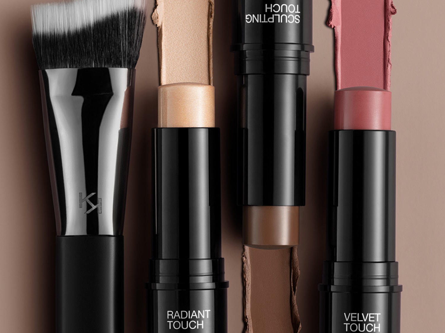 Nahaufnahme von Make-up-Produkten von Kiko Milano, darunter ein Pinsel, Radiant Touch Highlighter, Sculpting Touch Konturierstift und Velvet Touch Blush, alle in eleganten schwarzen Verpackungen.