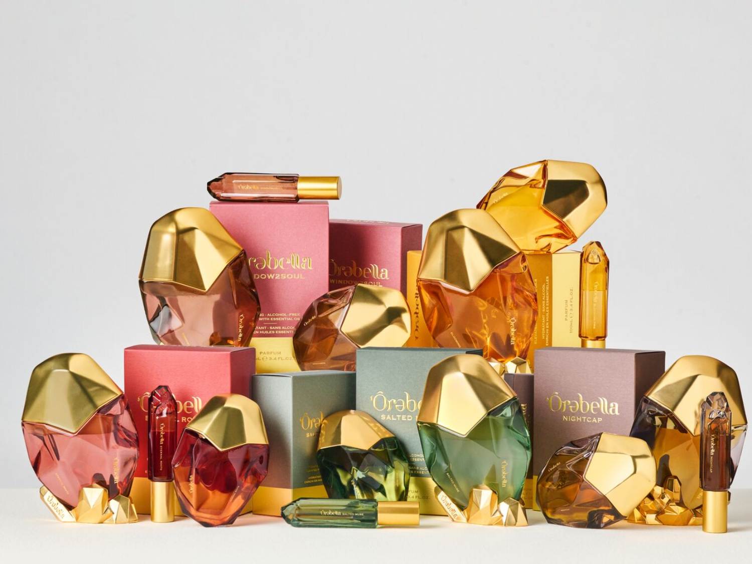 Elegancka kolekcja perfum Orabella w różnych kolorach i zapachach, prezentowana na białym tle, idealna na prezent.