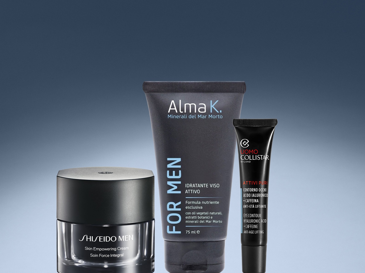Tre prodotti di bellezza maschile su sfondo blu sfumato: crema viso Shiseido Men in vasetto nero, trattamento idratante Alma K. in tubo grigio e contorno occhi Uomo Collistar in confezione nera.