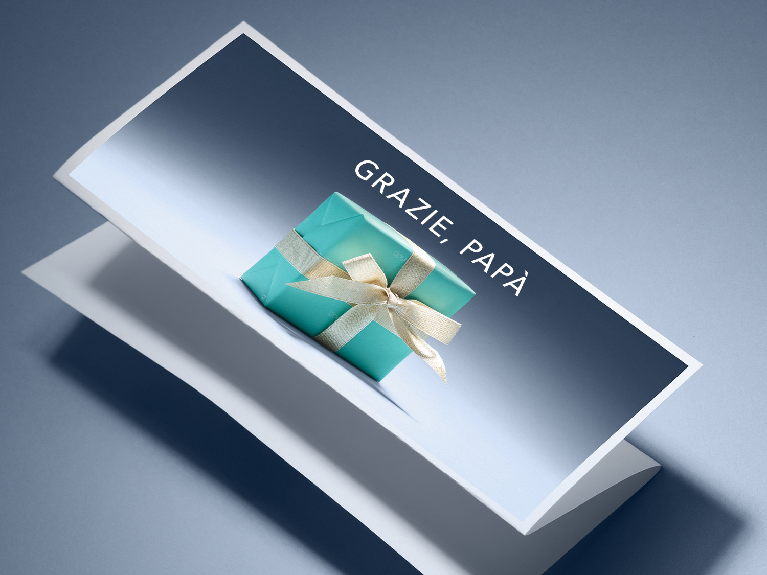 Confezione regalo turchese con nastro dorato e la scritta 'Grazie, Papà' su sfondo blu.