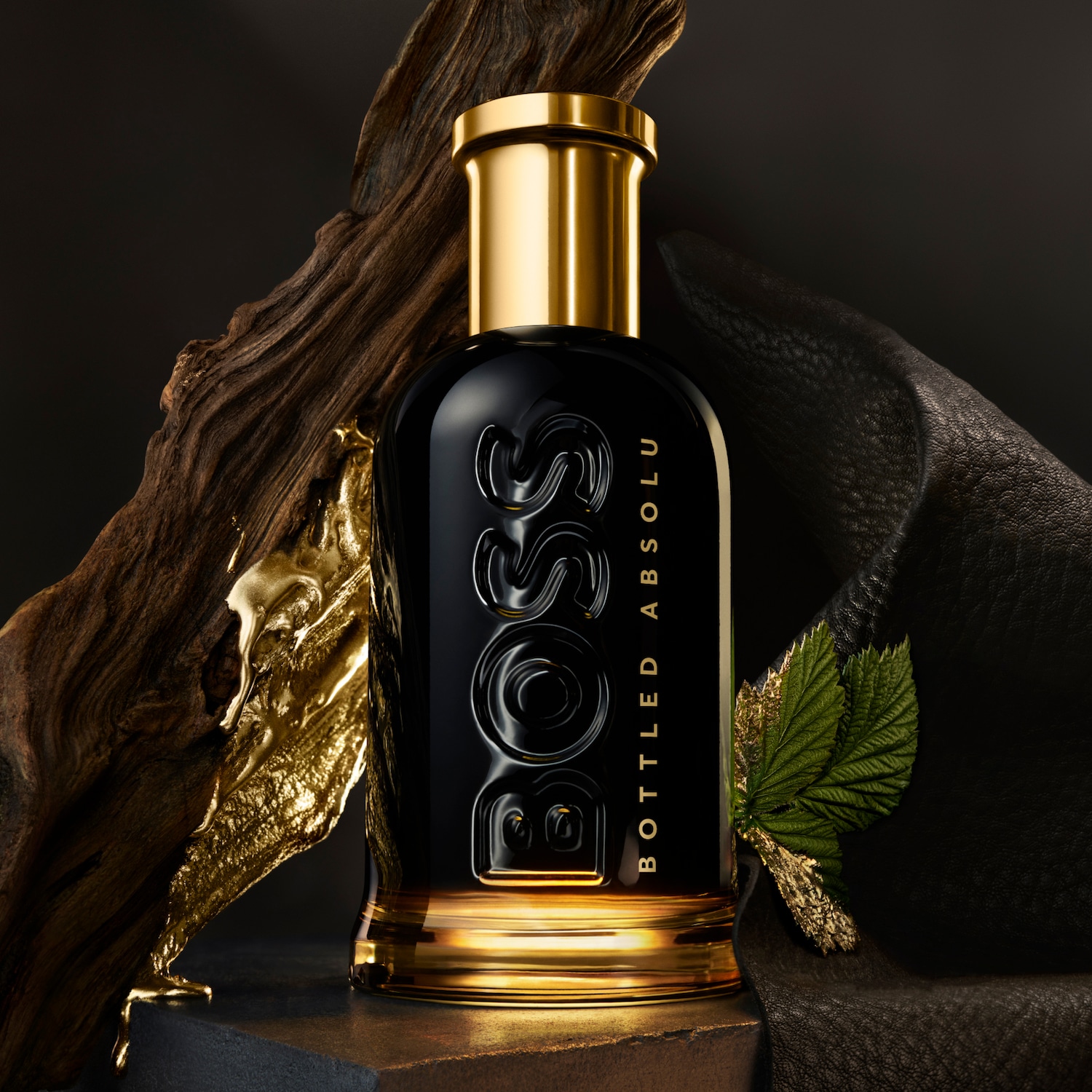 Czarny flakon perfum BOSS Bottled Absolu z złotymi akcentami, umieszczony na tle z teksturą drewna i skóry, emanuje luksusem i męską elegancją.