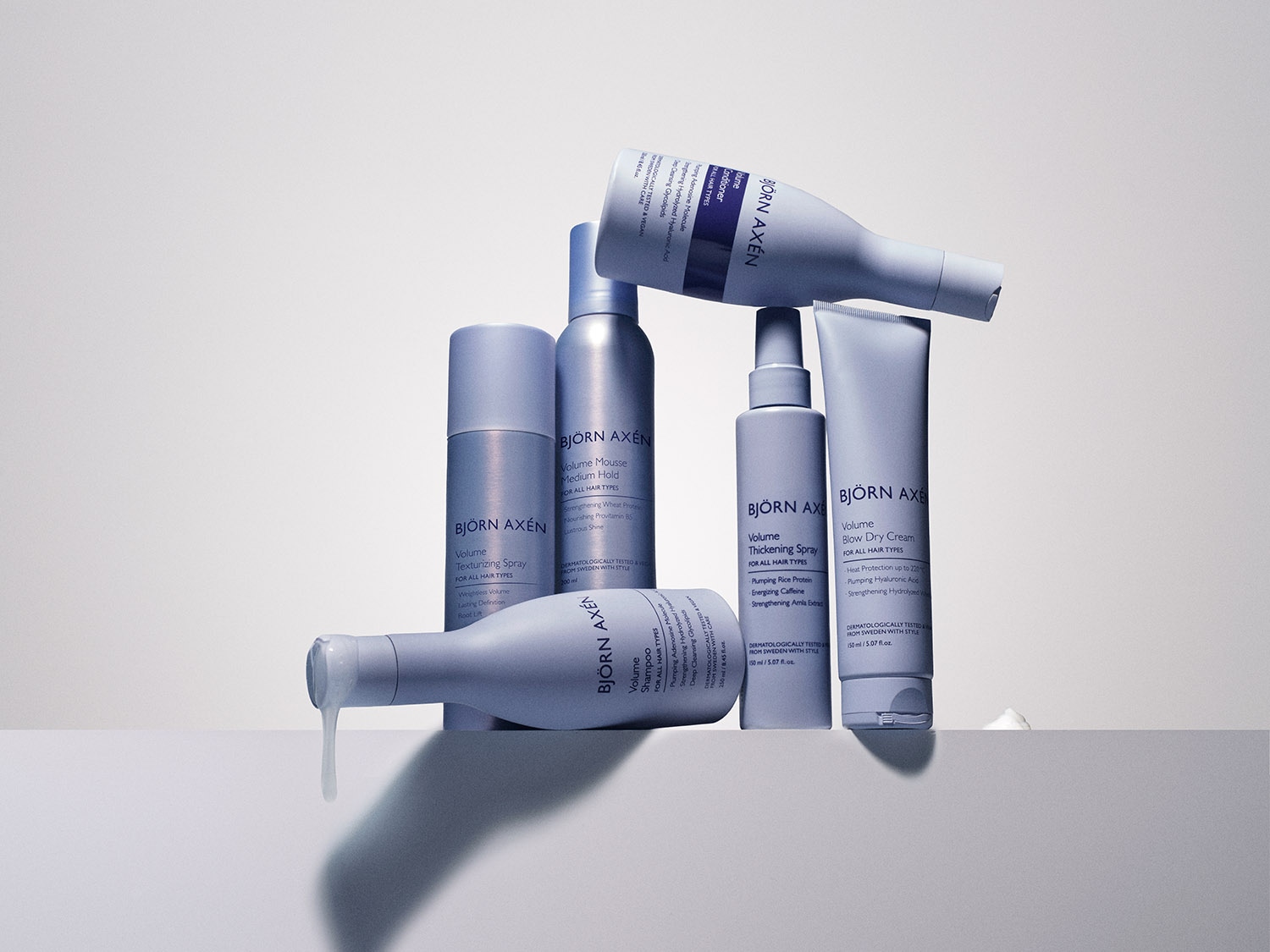 Kolekcja produktów Björn Axén do stylizacji włosów, w pastelowych opakowaniach: spray teksturyzujący, mus do włosów, szampon zwiększający objętość, spray pogrubiający i krem do suszenia.