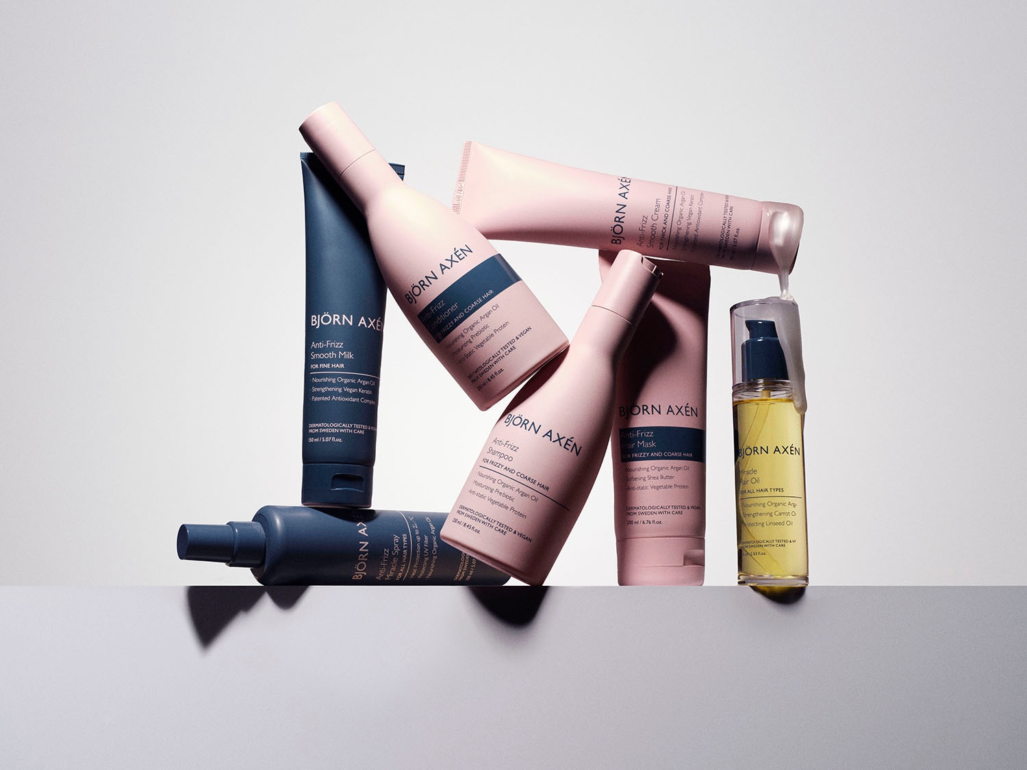 Różne produkty do włosów Björn Axén Anti-Frizz, w tym szampon, odżywka, maska, krem, mleczko i olejek, które zawierają organiczny olej arganowy i proteiny roślinne.