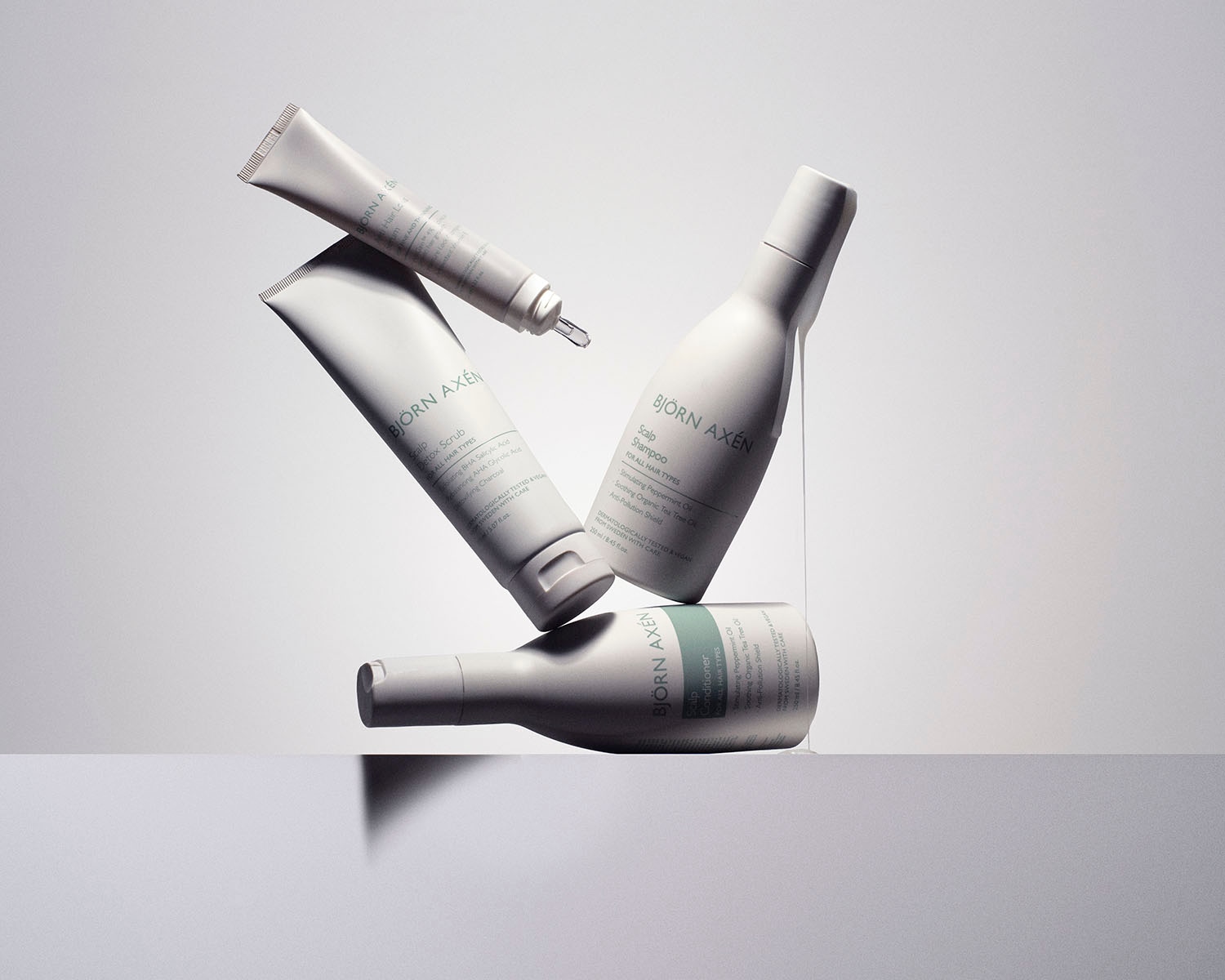 Na zdjęciu znajdują się produkty do pielęgnacji skóry głowy marki Björn Axén, w tym peeling detoksykujący, szampon i odżywka, wszystkie w białych opakowaniach.