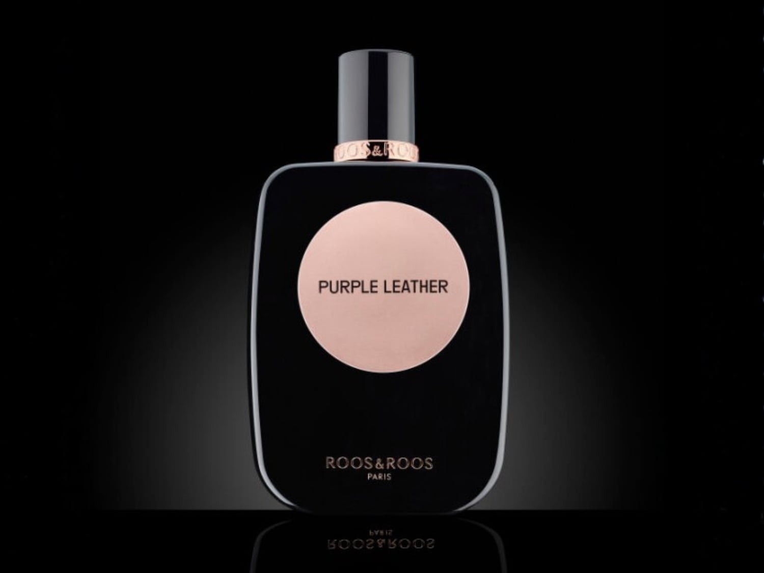 Découvrez le parfum Purple Leather de Roos&Roos Paris, présenté dans un élégant flacon noir avec un médaillon rose portant le nom du parfum.