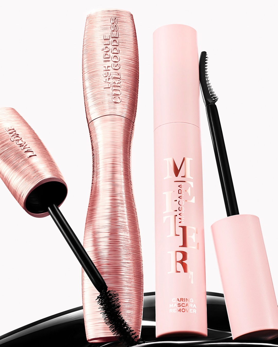 Lancôme mascara's, waaronder Lash Idôle Curl Goddess in een roségouden verpakking en een Caring Mascara Remover in een zachtroze verpakking, beide met zwarte borstels.