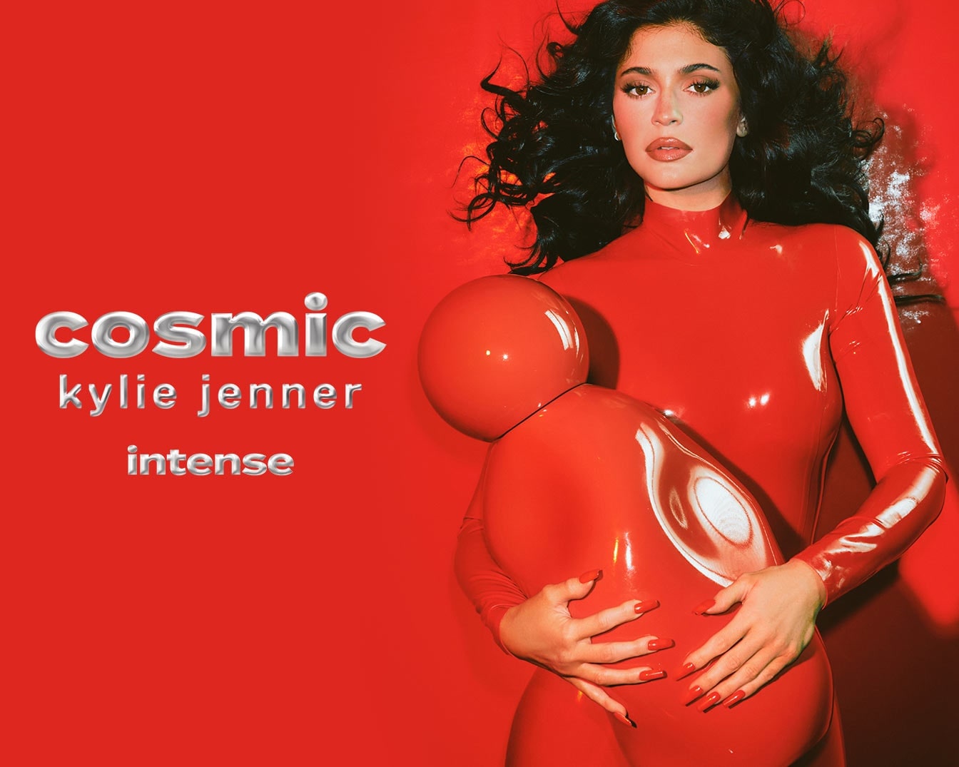 Kylie Jenner pose dans une combinaison rouge brillante, tenant une forme abstraite rouge, avec le texte "cosmic kylie jenner intense" sur un fond rouge.