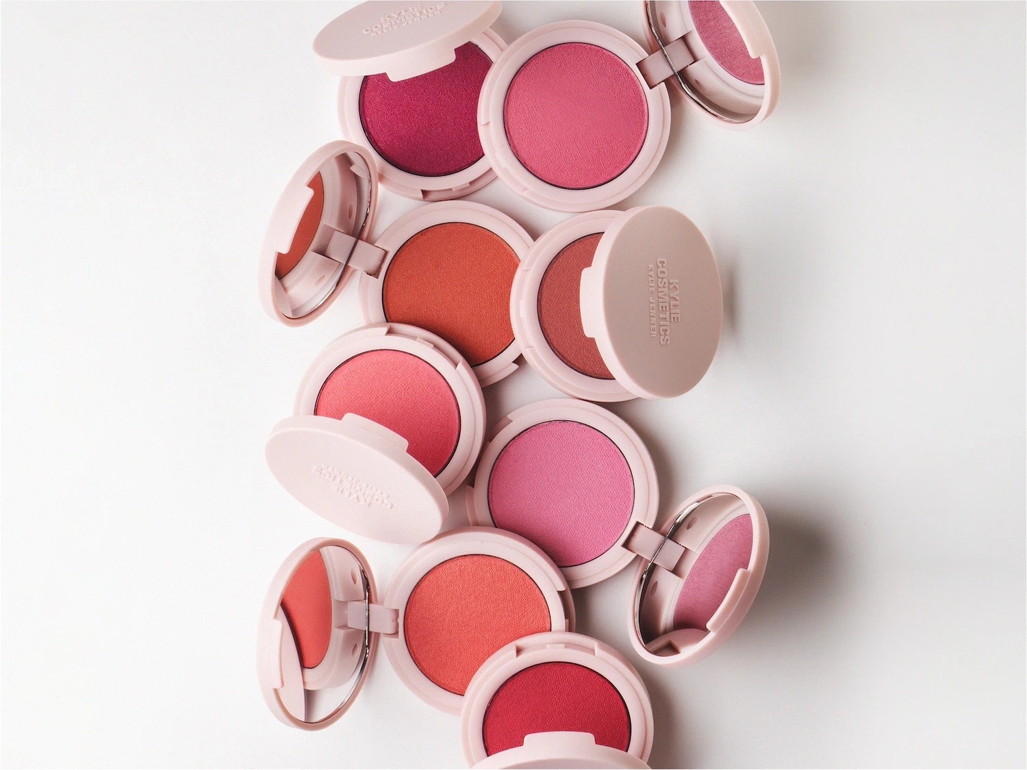 Une collection de blushs Kylie Cosmetics aux teintes rose, rouge et orange, présentés dans des boîtiers ronds et beiges.