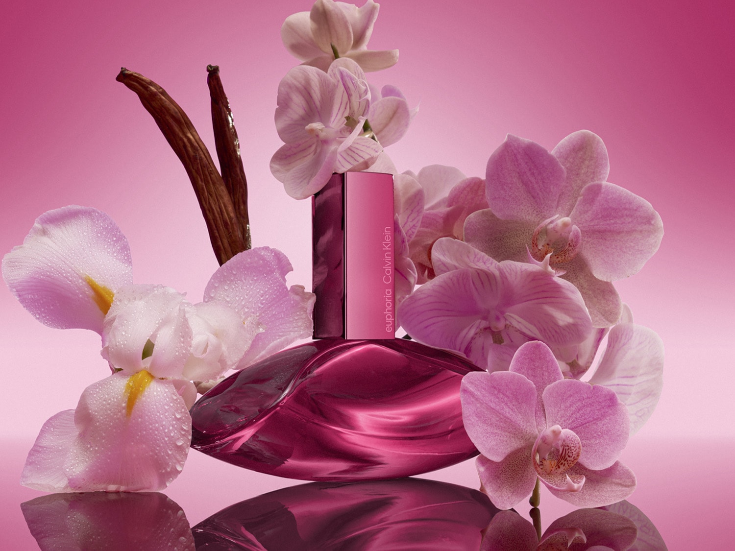 Ružový flakón parfému Calvin Klein Euphoria obklopený kvetmi orchideí a vanilkovými strukmi na ružovom pozadí.