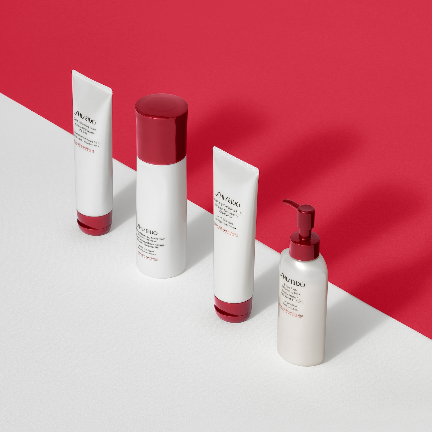 Una gamma di prodotti Shiseido per la pulizia del viso, tra cui schiume detergenti e latte detergente, presentati su uno sfondo bicolore bianco e rosso.