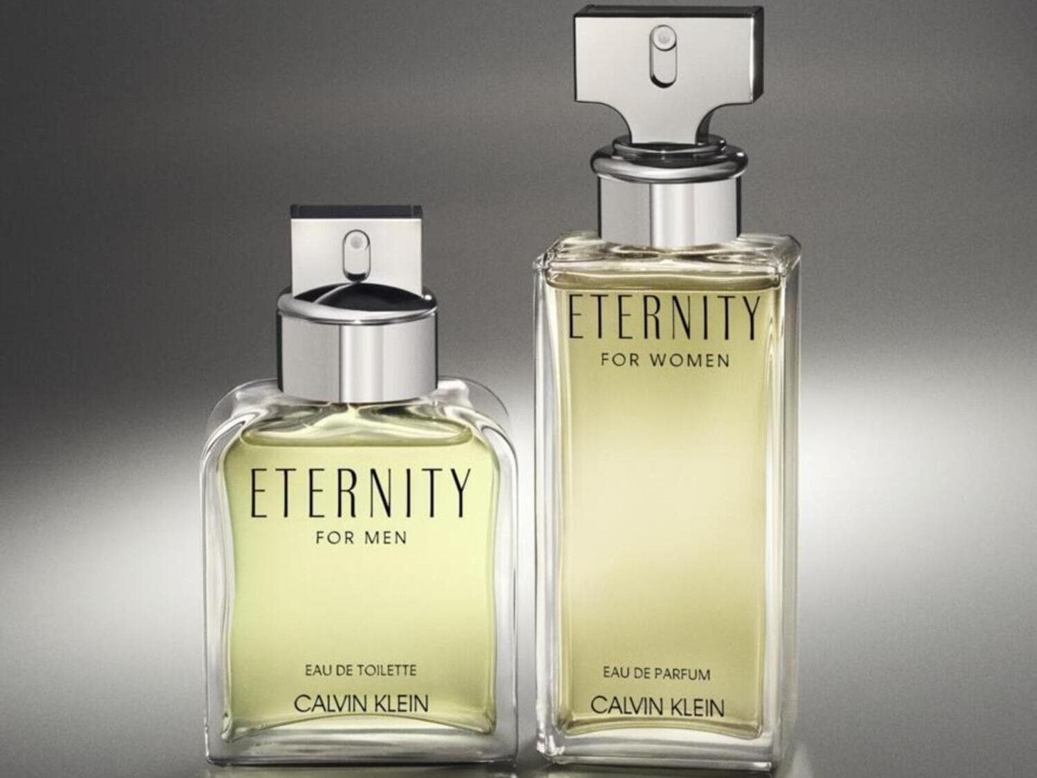 Dos frascos de perfume Eternity de Calvin Klein, uno para hombre en Eau de Toilette y otro para mujer en Eau de Parfum, ambos con envases de vidrio transparente y tapones plateados.