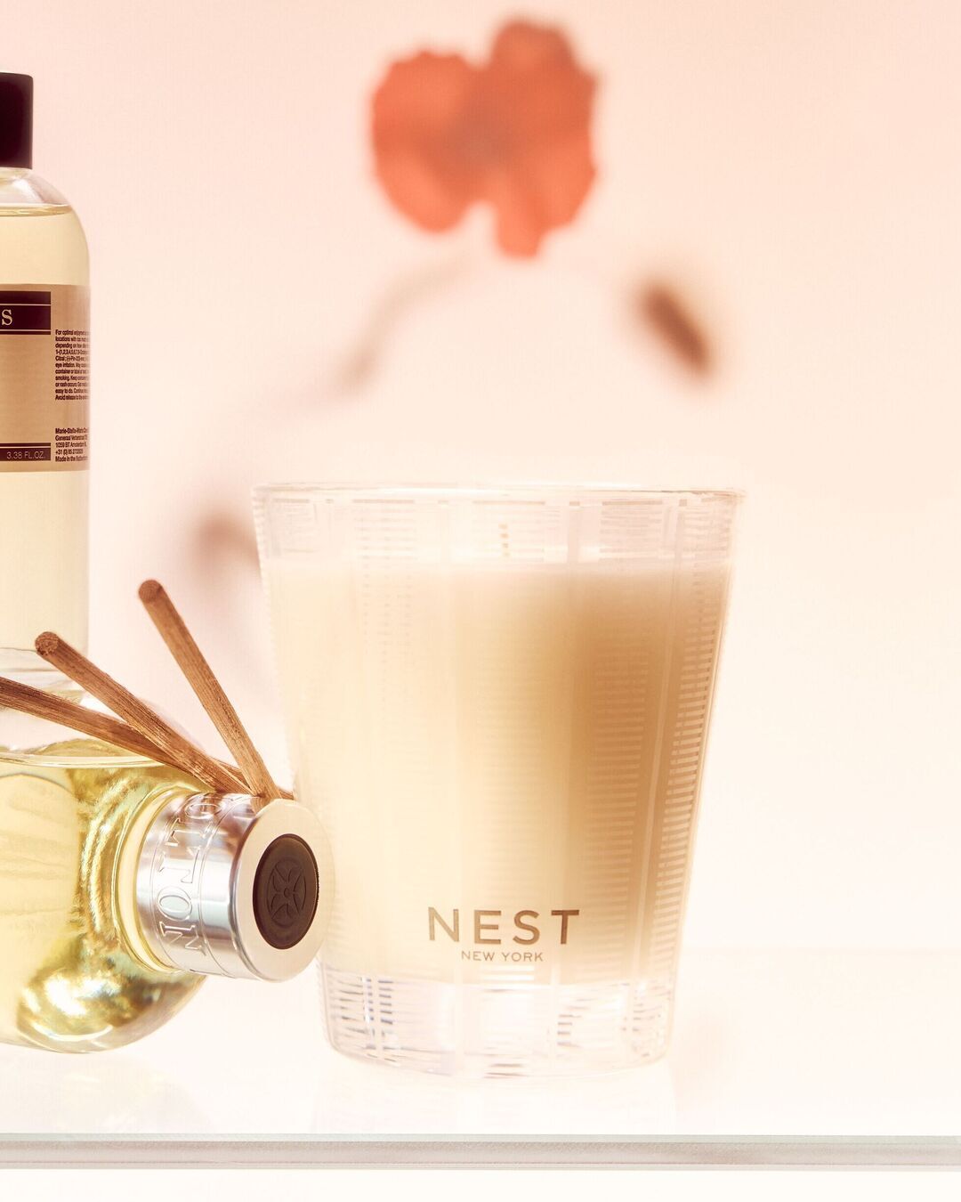 NEST New York žvakė stikliniame indelyje ir skystas oro gaiviklis su lazdelėmis, skirti jaukiai atmosferai sukurti.