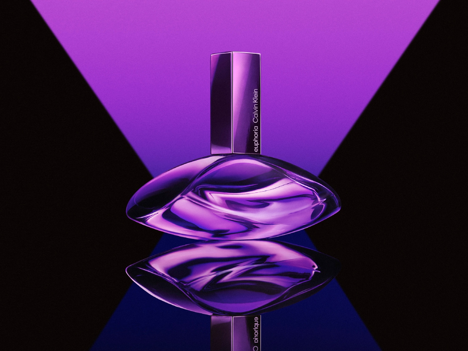 Fioletowy flakon perfum Euphoria Calvin Klein o abstrakcyjnym kształcie, odbijający się w błyszczącej powierzchni, na tle fioletowo-czarnym.