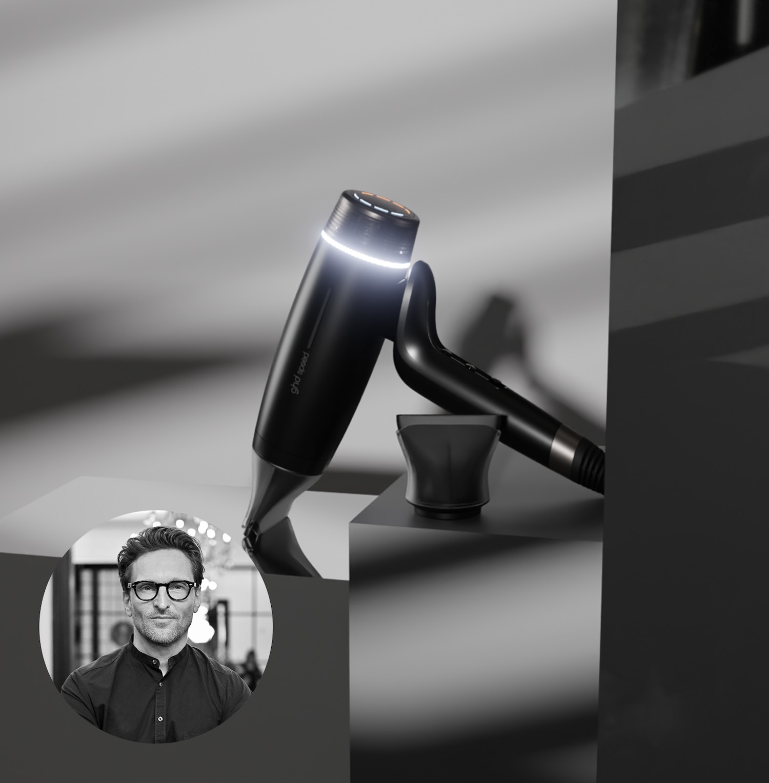 Schwarzer Haartrockner mit Aufsatz und einem Porträt eines Mannes mit Brille, der das Produkt präsentiert.